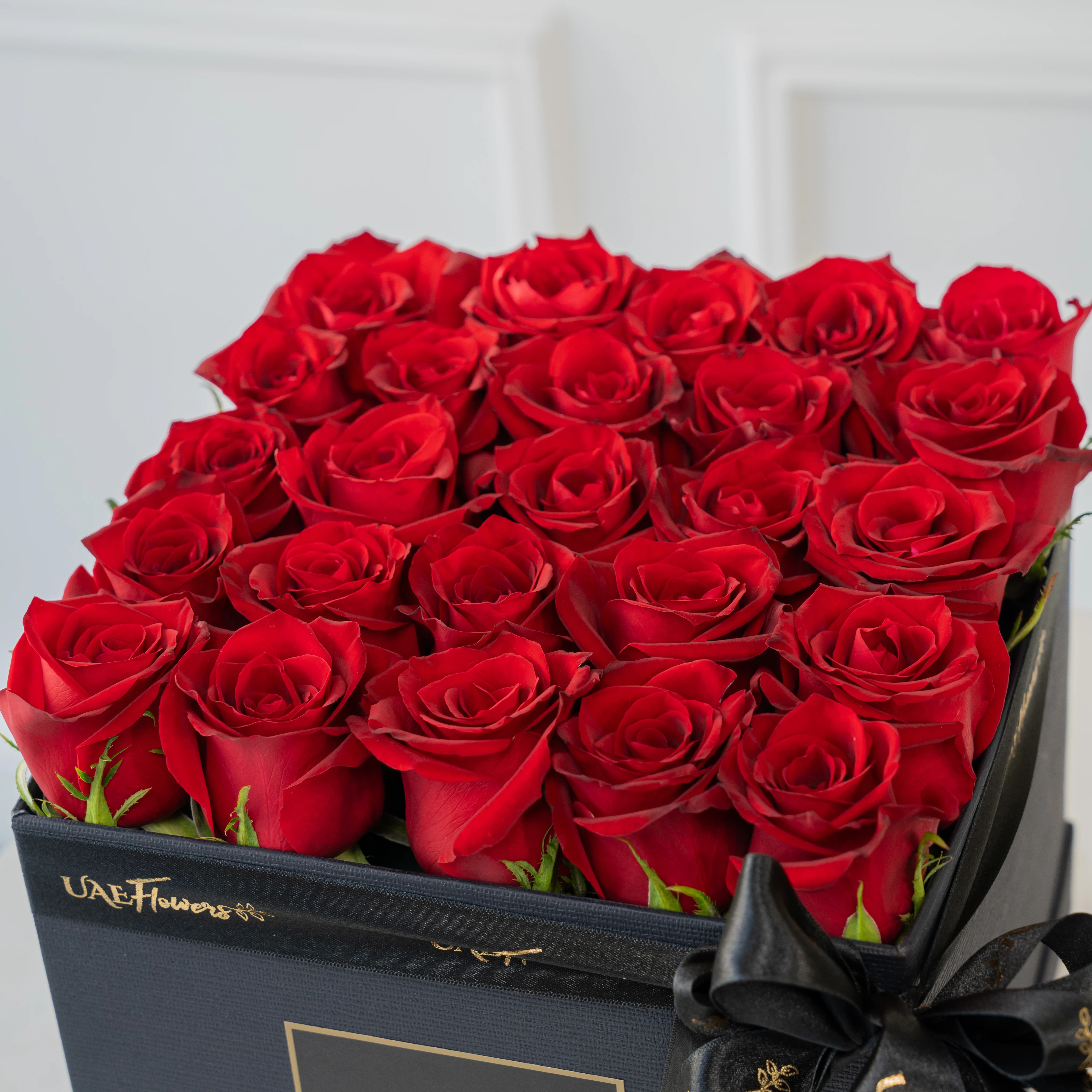 An Arrangement of 12 Red Roses in a Square Black Box