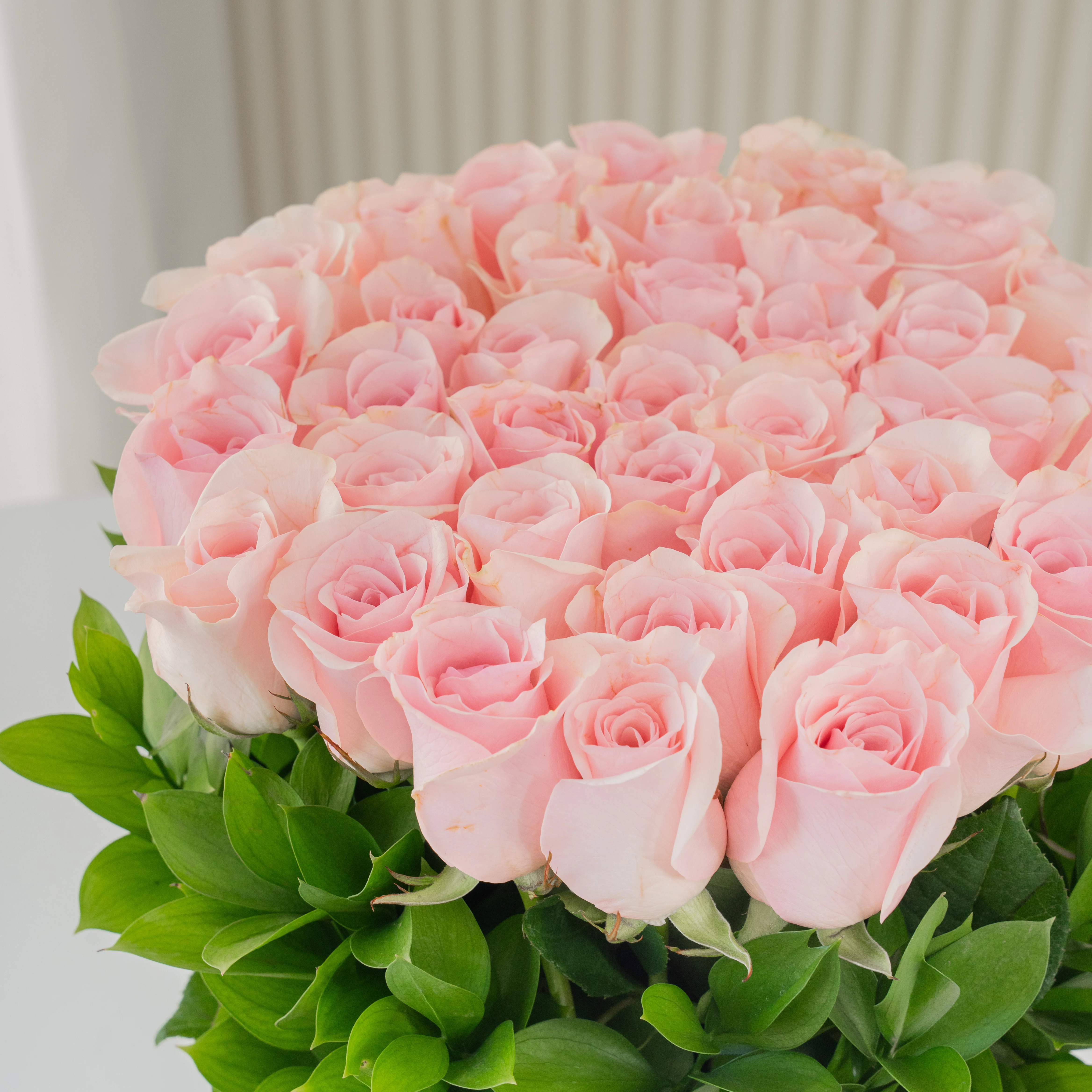 24 pink roses with green fillers in a round basket.