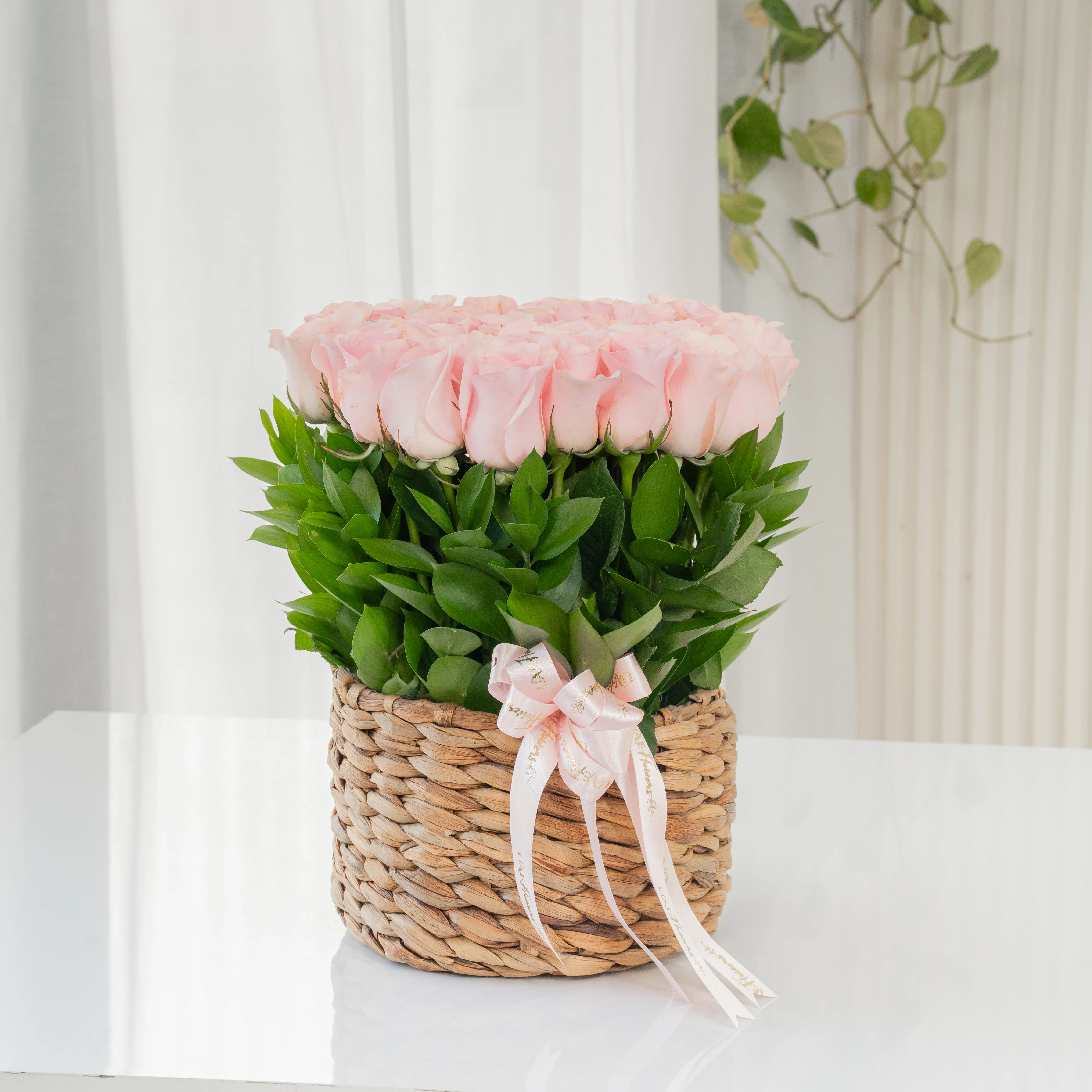 24 pink roses with green fillers in a round basket.