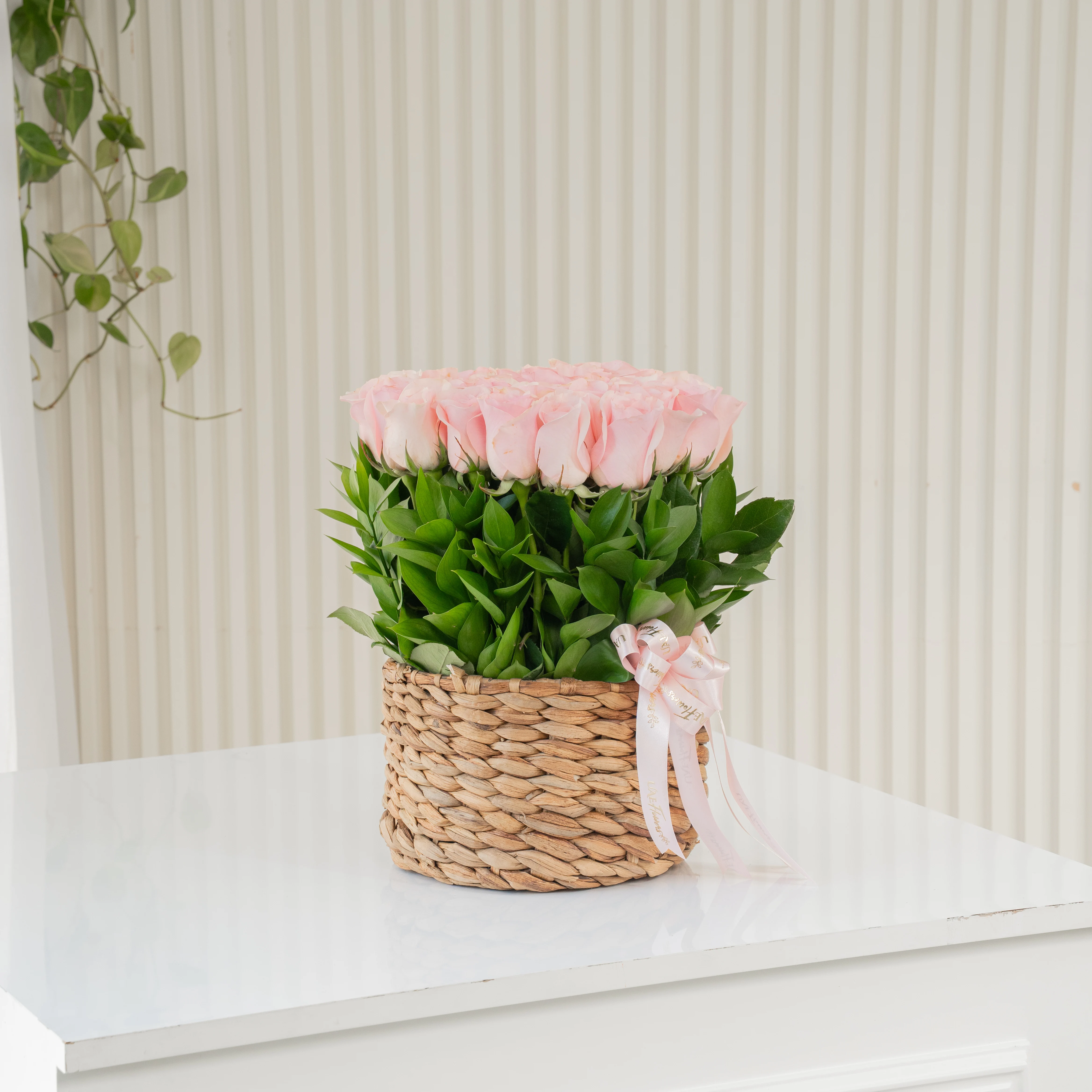 24 pink roses with green fillers in a round basket.