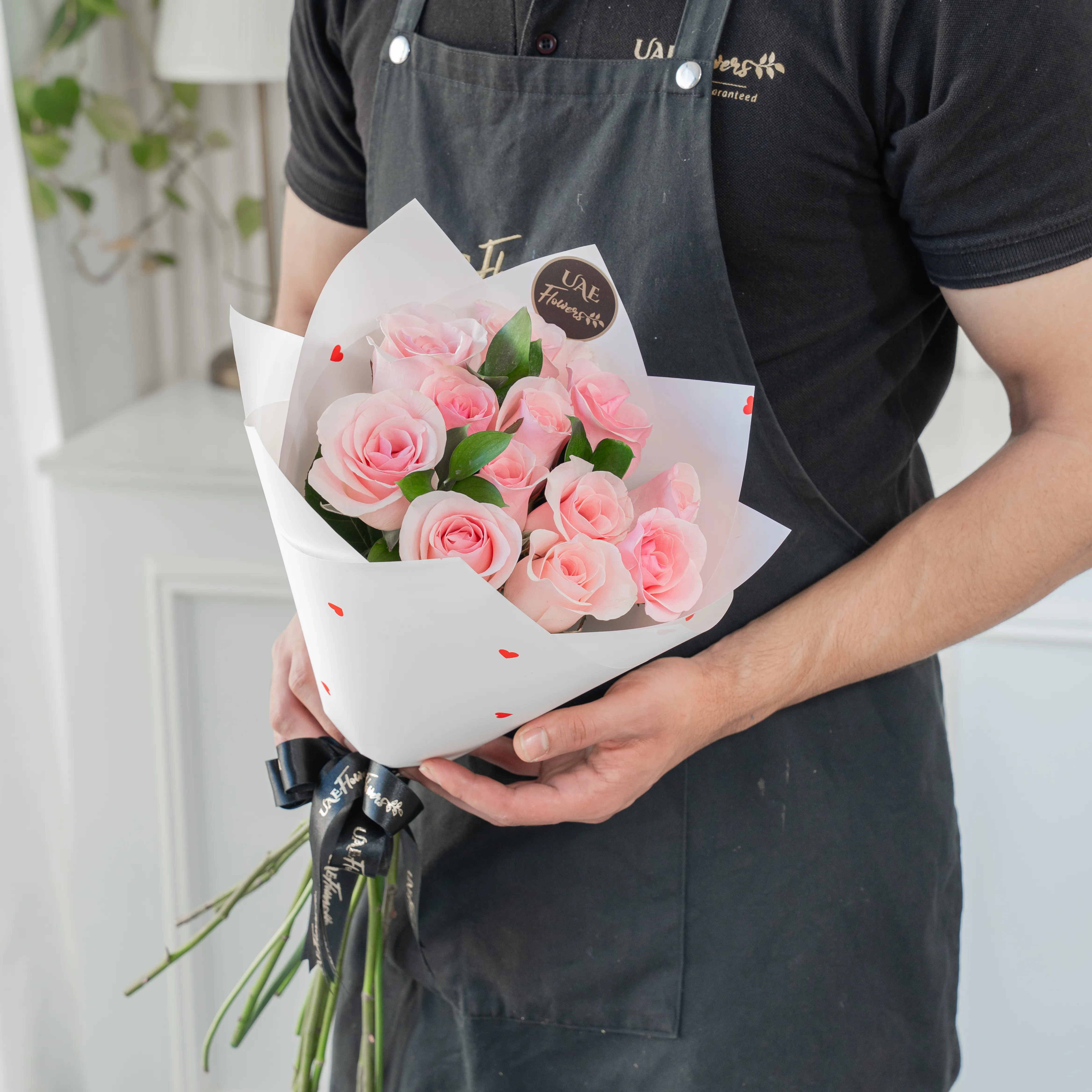 Bouquet of 10 pink roses in paper packing hand-tied with ribbons.