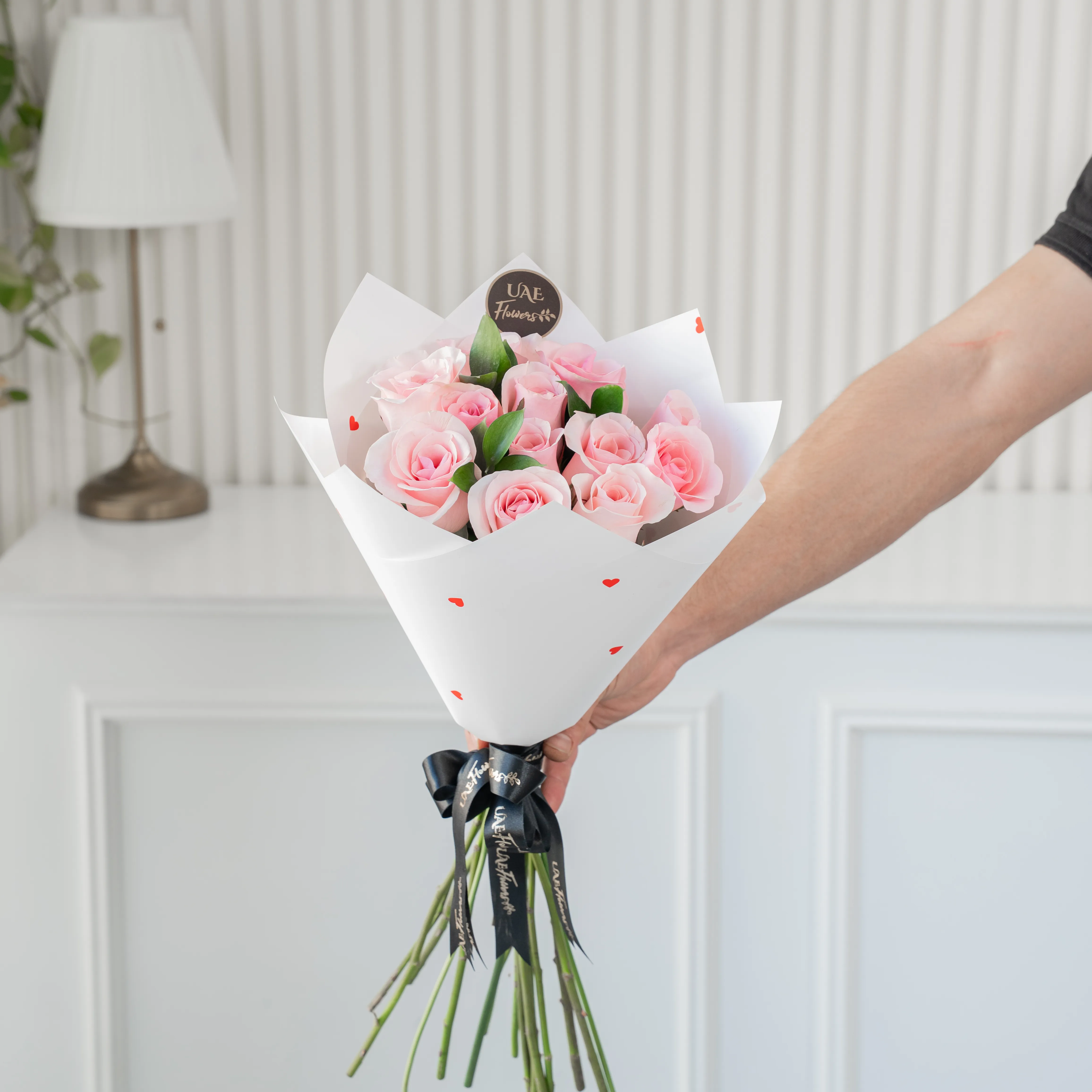 Bouquet of 10 pink roses in paper packing hand-tied with ribbons.