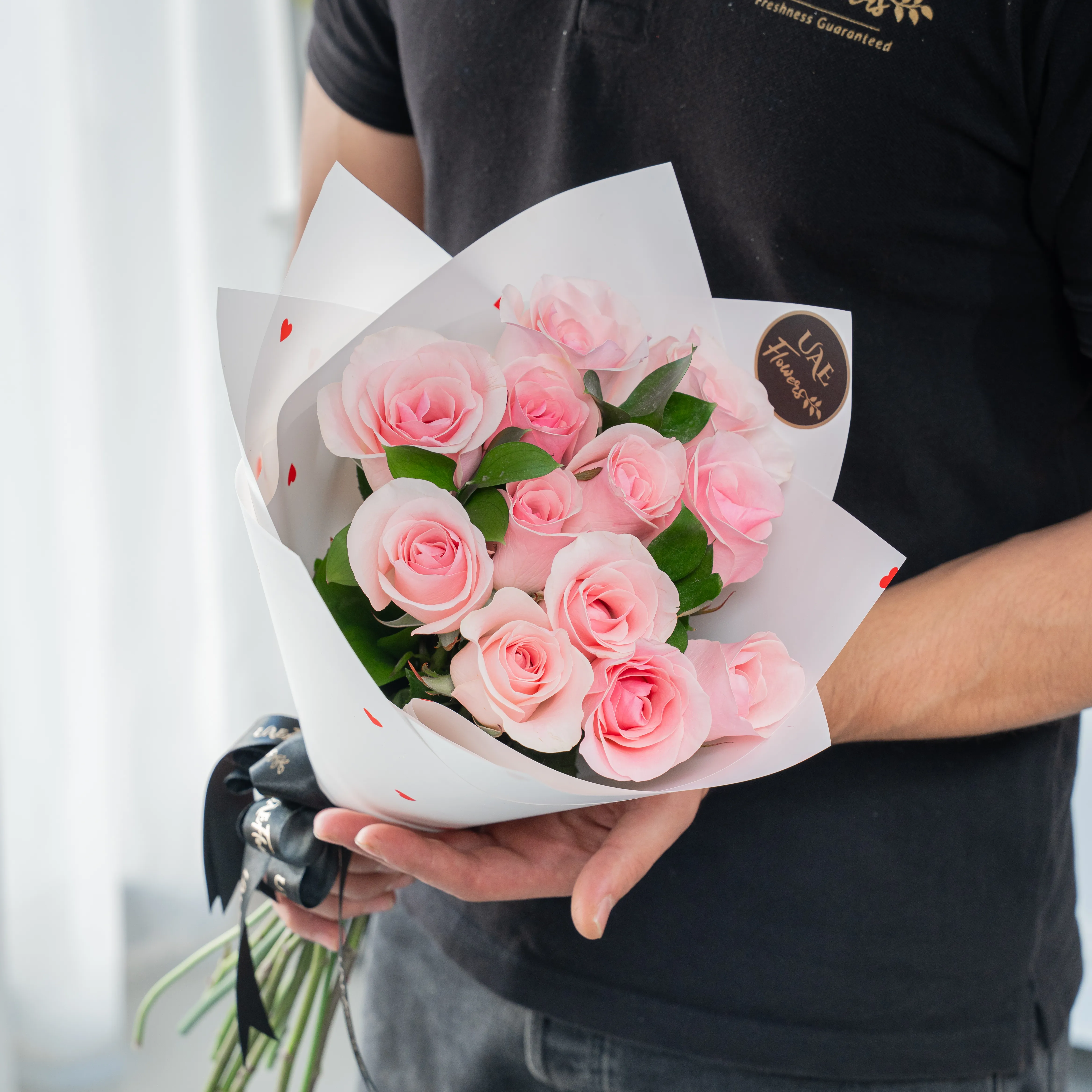 Bouquet of 10 pink roses in paper packing hand-tied with ribbons.