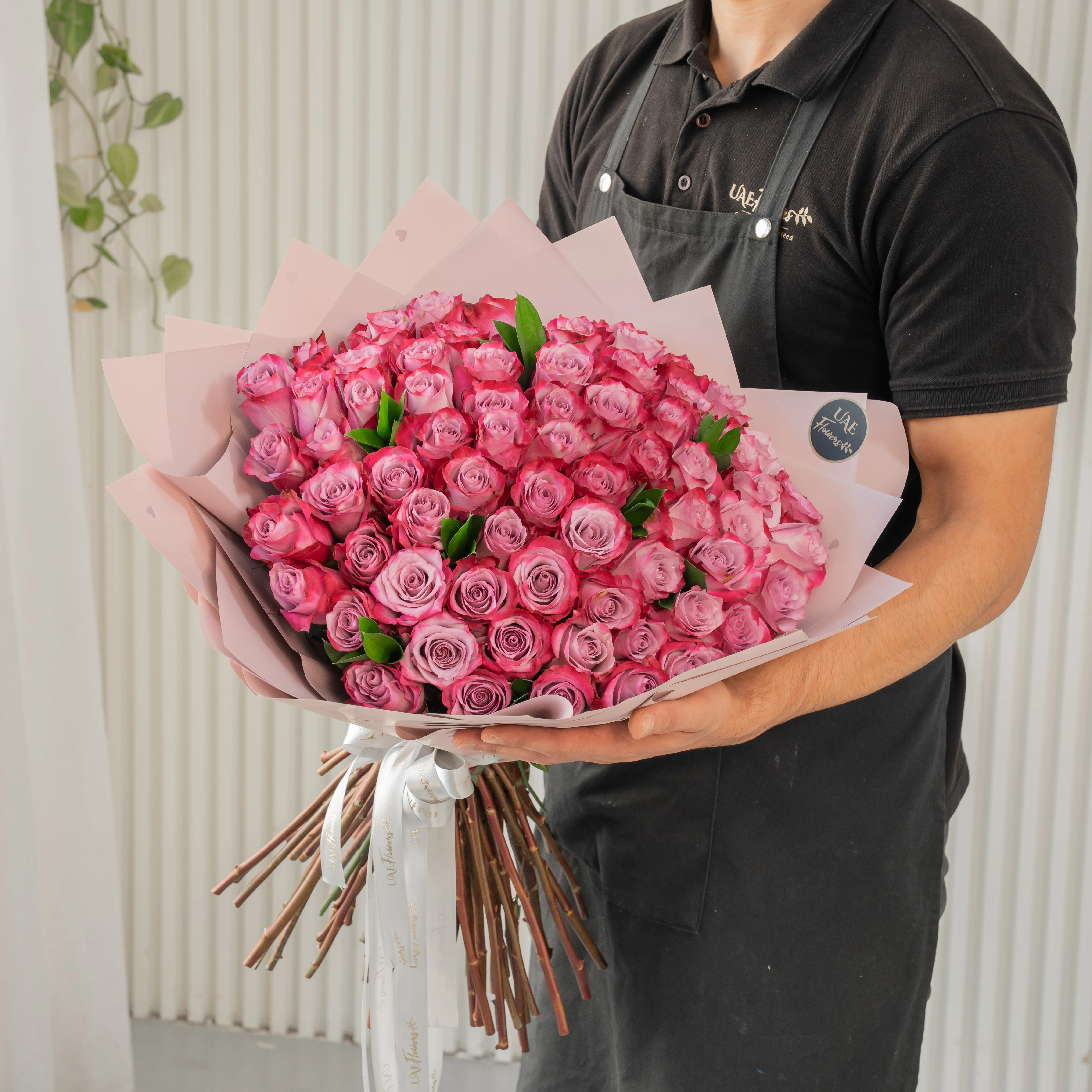 Bouquet of 40 purple roses in paper packing hand-tied with ribbons.