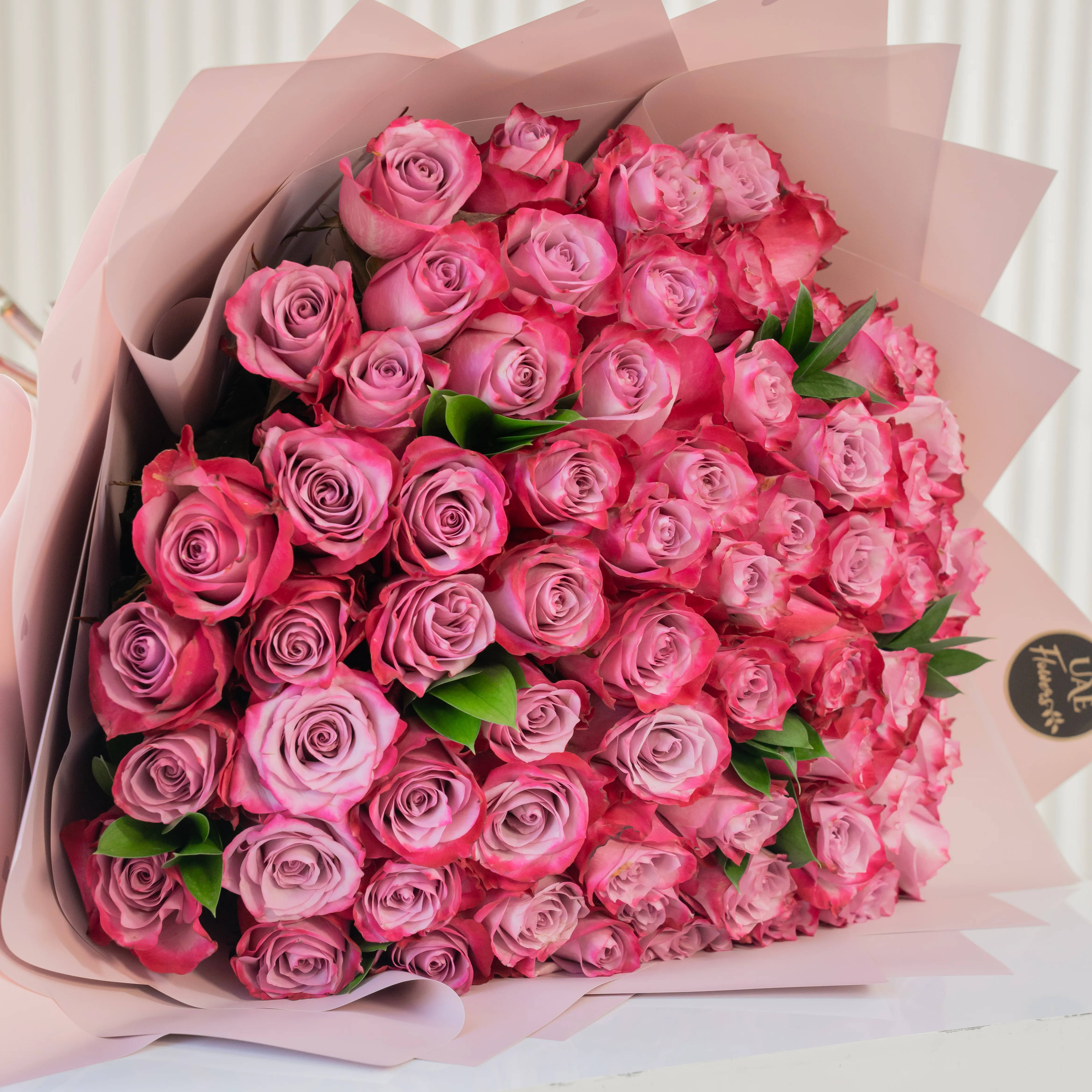 Bouquet of 40 purple roses in paper packing hand-tied with ribbons.