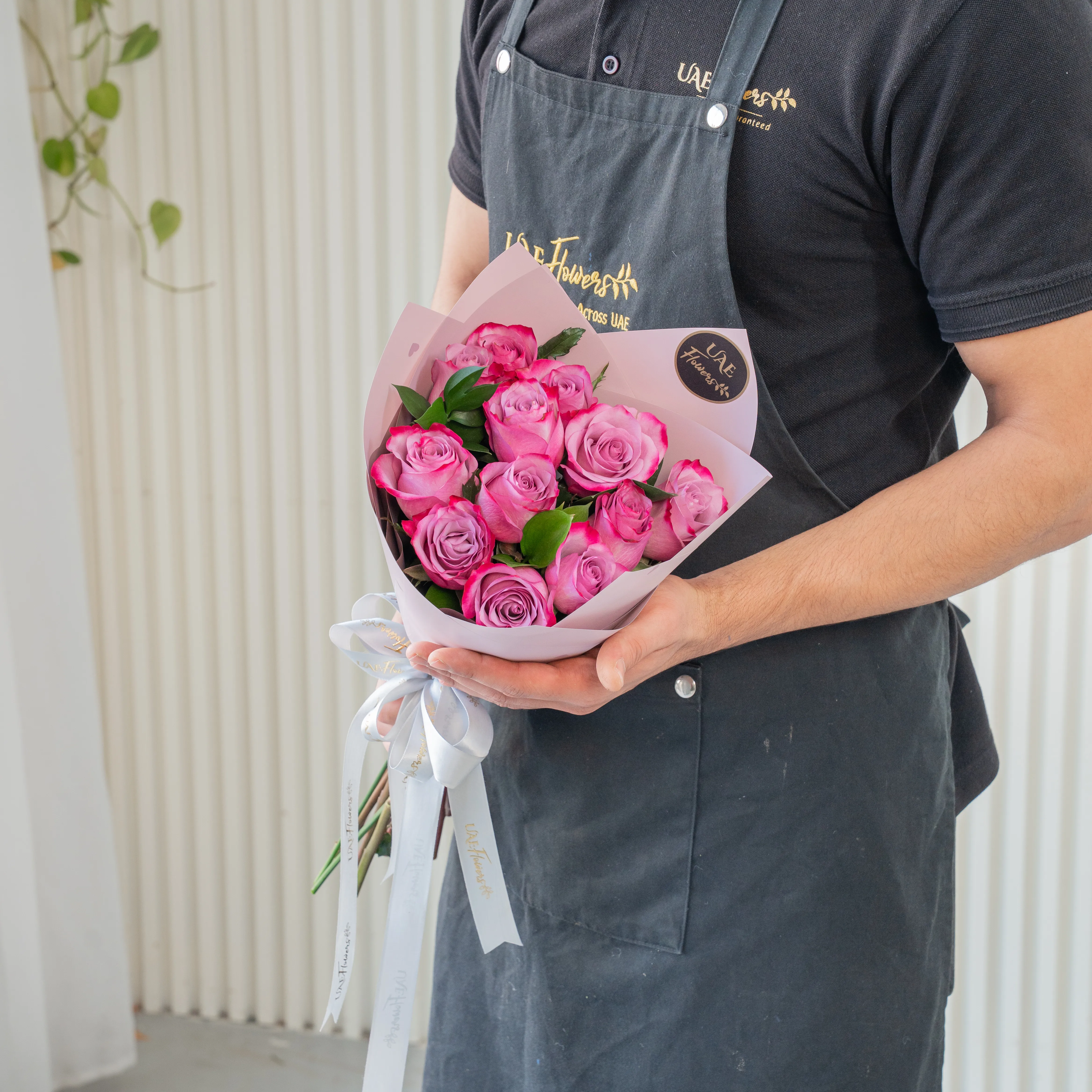 Bouquet of 10 purple roses in paper packing hand-tied with ribbons.