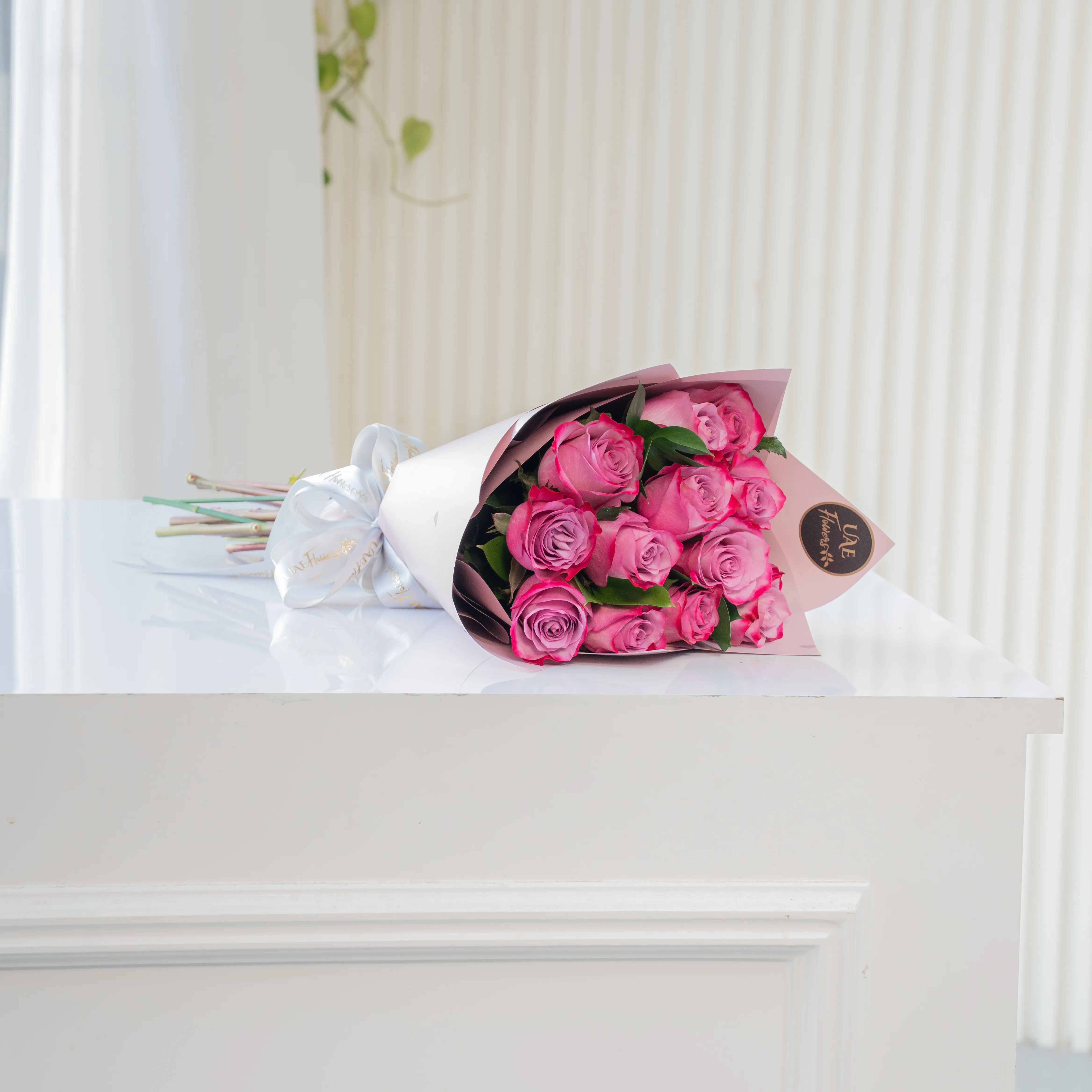 Bouquet of 10 purple roses in paper packing hand-tied with ribbons.