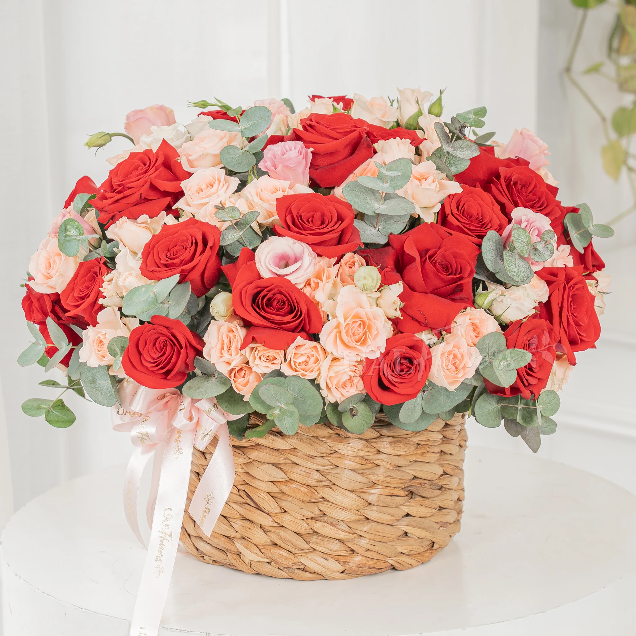 22 red roses and 12 pink spray roses with fillers in a round basket.