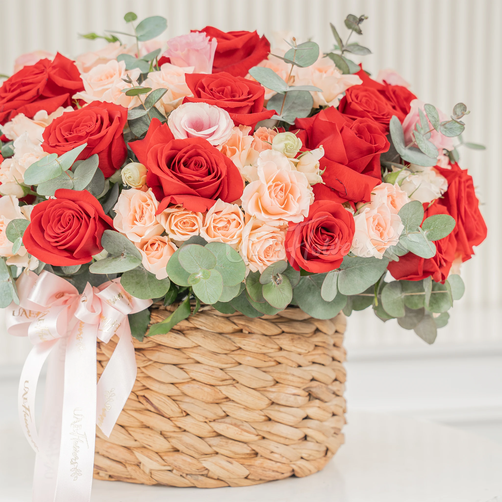 22 red roses and 12 pink spray roses with fillers in a round basket.