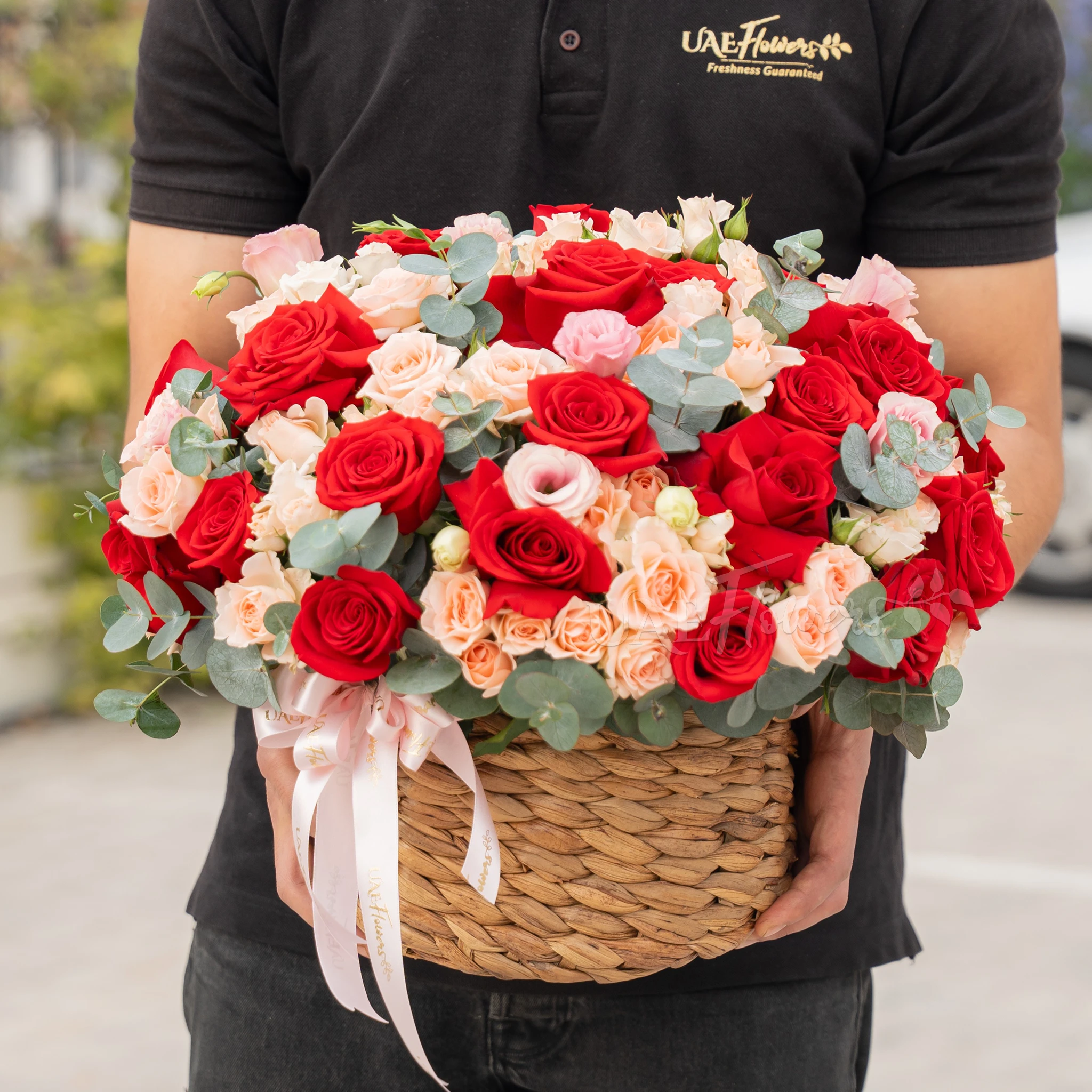 22 red roses and 12 pink spray roses with fillers in a round basket.