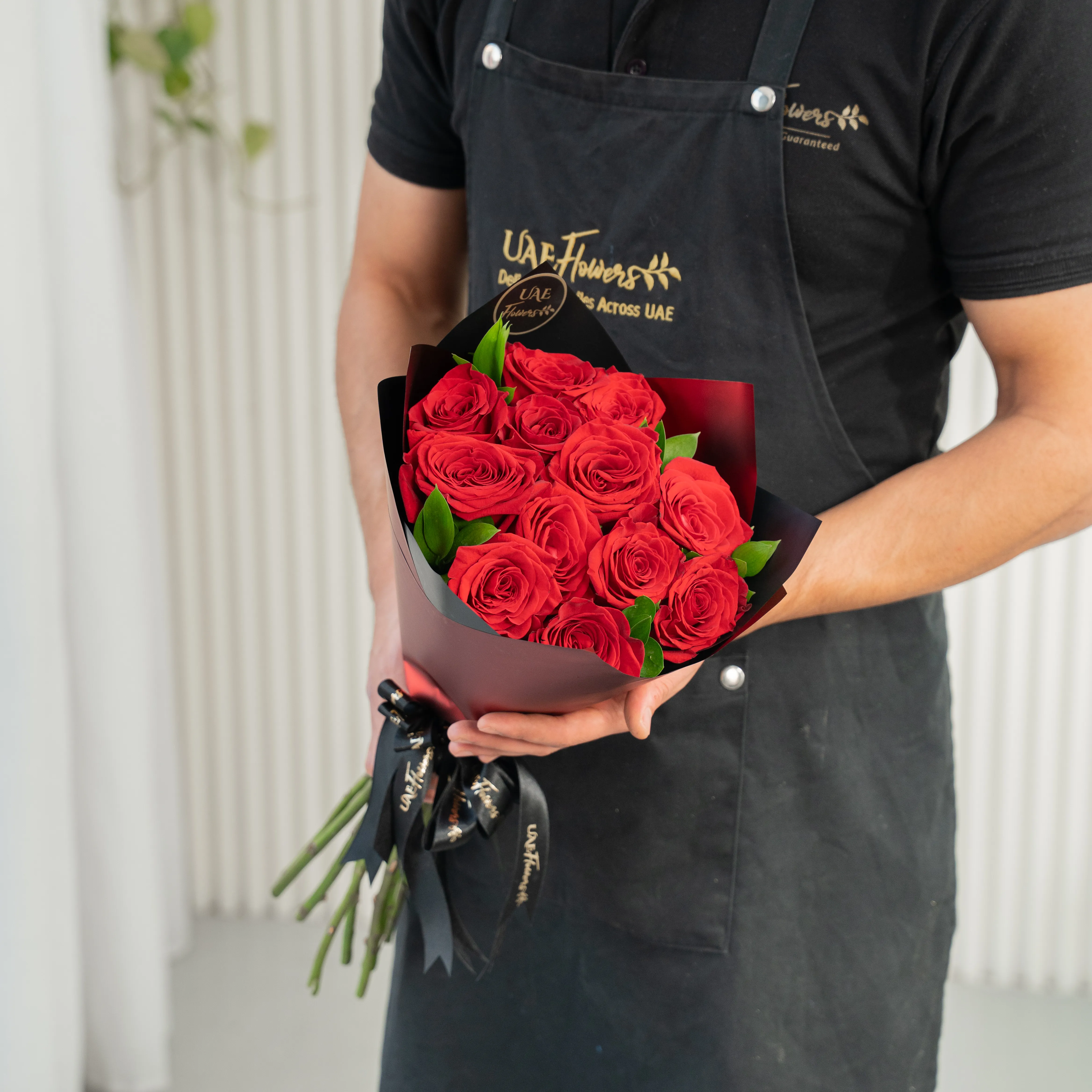 Bouquet of 10 red roses in paper packing hand-tied with ribbons.