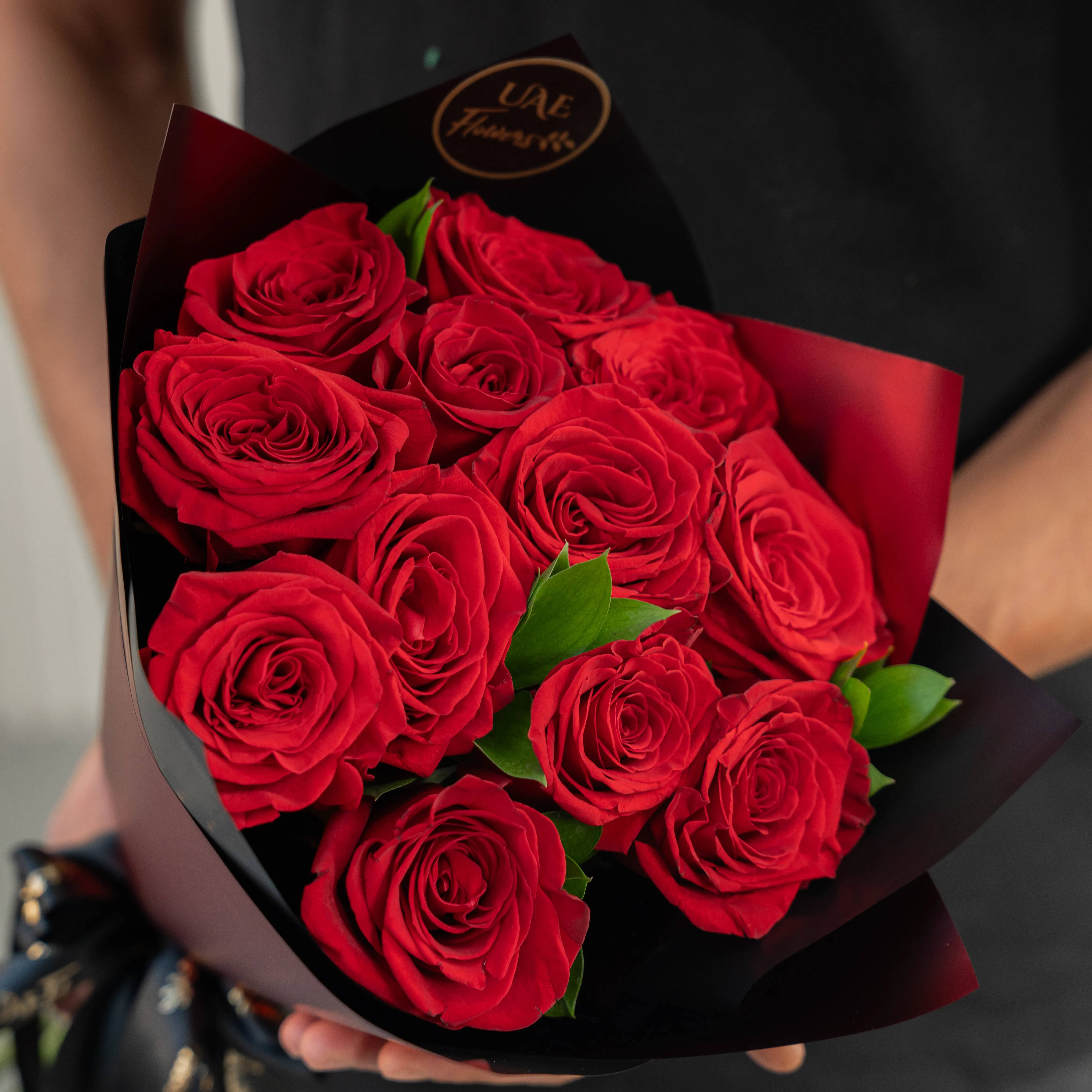 Bouquet of 10 red roses in paper packing hand-tied with ribbons.