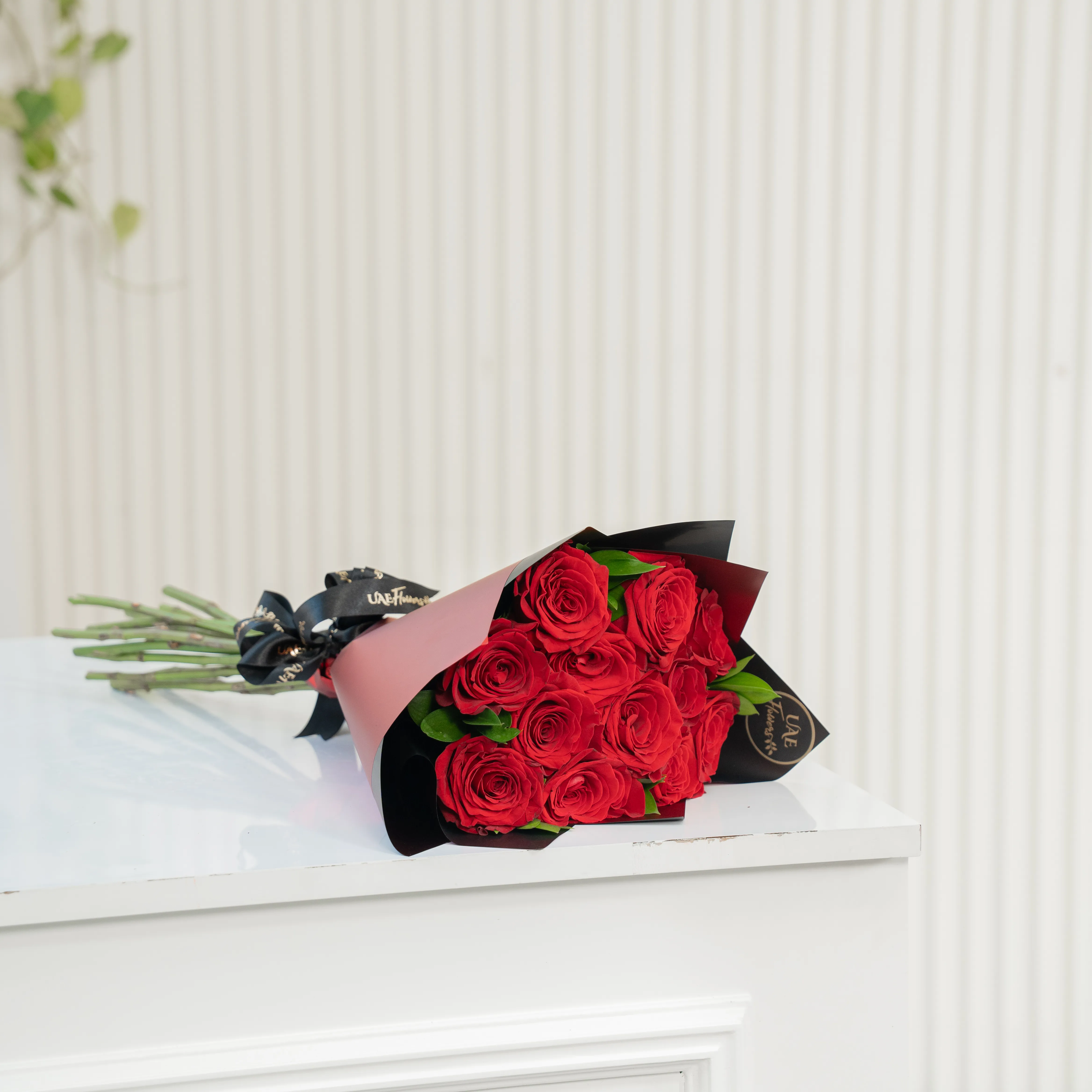 Bouquet of 10 red roses in paper packing hand-tied with ribbons.