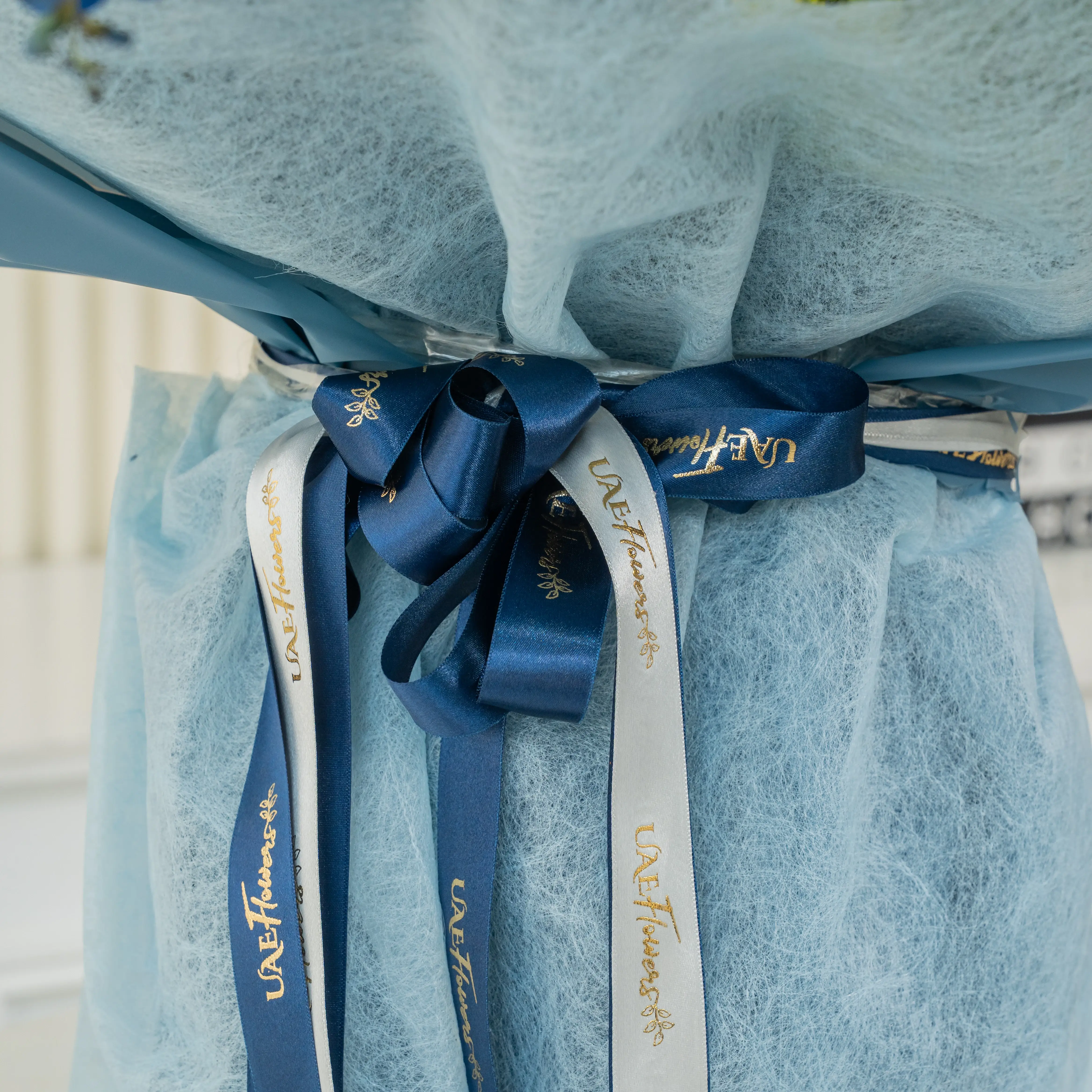 Bouquet of 8 sunflowers, 4 red roses, 5 blue hydrangeas, 6 carnations, green button chrysanthemums, blue sprayed eucalyptus leaf with green fillers in blue paper packing tied with blue ribbons.