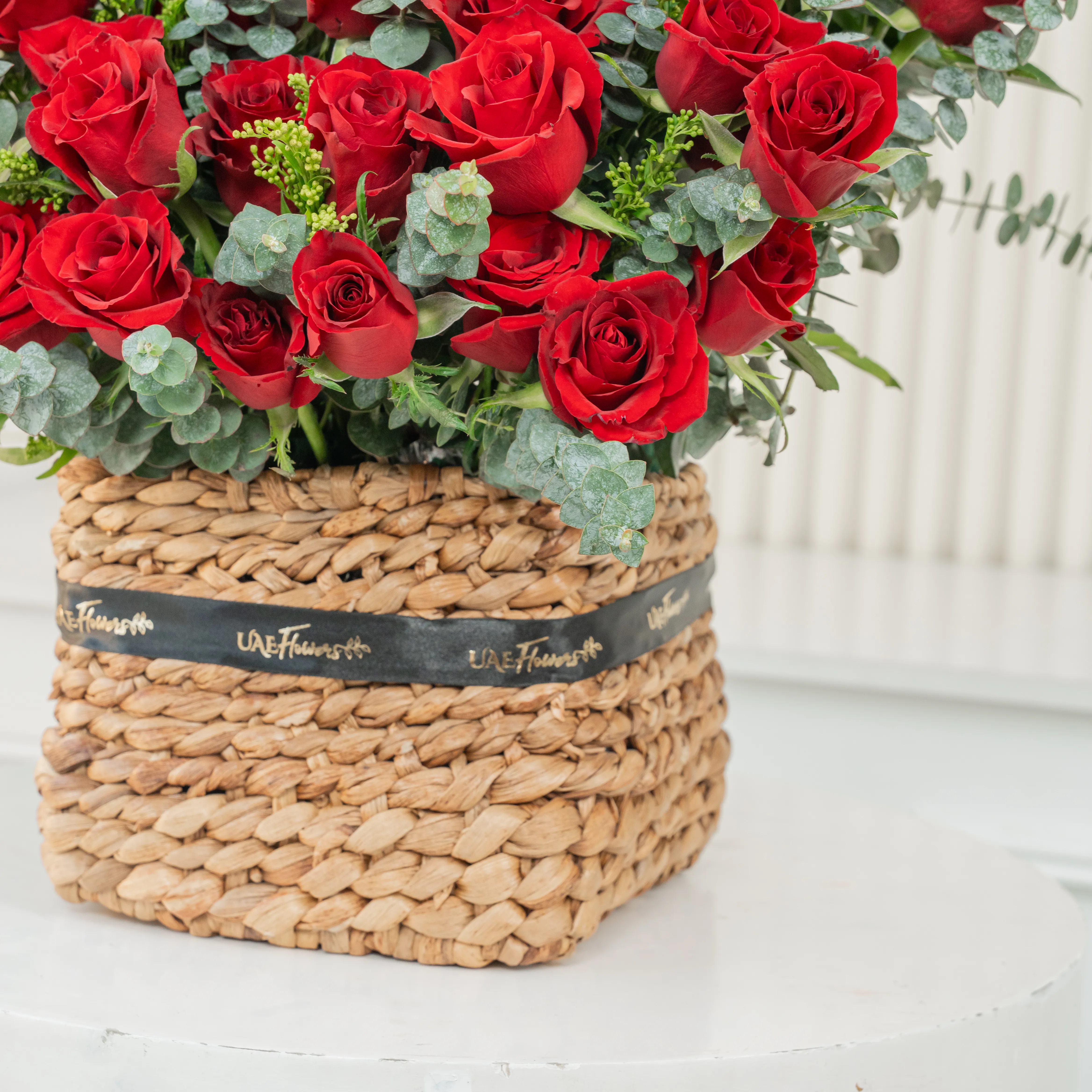 40 red roses with eucalyptus leaf in a square basket.
