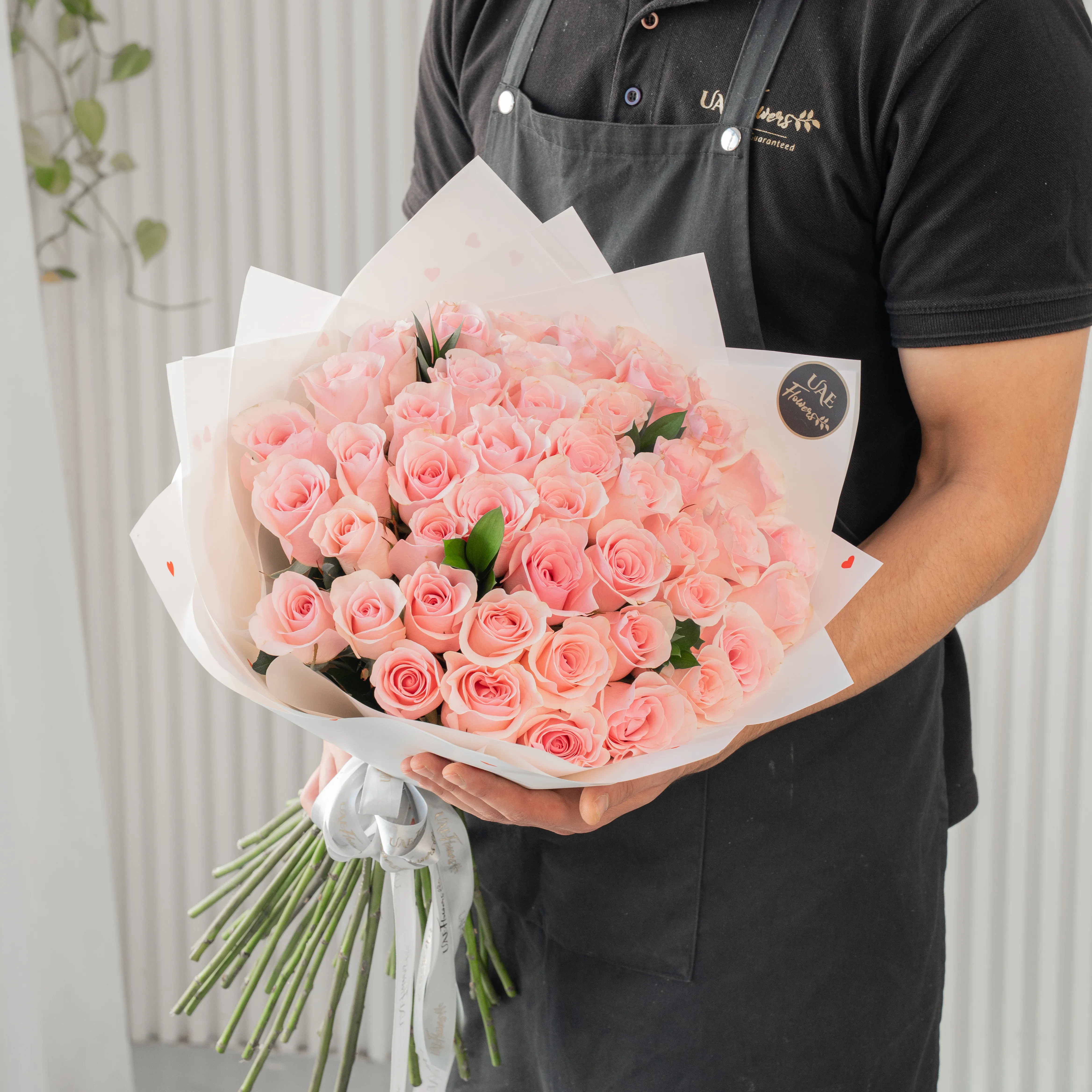 Bouquet of 30 pink roses in paper packing hand-tied with ribbons.