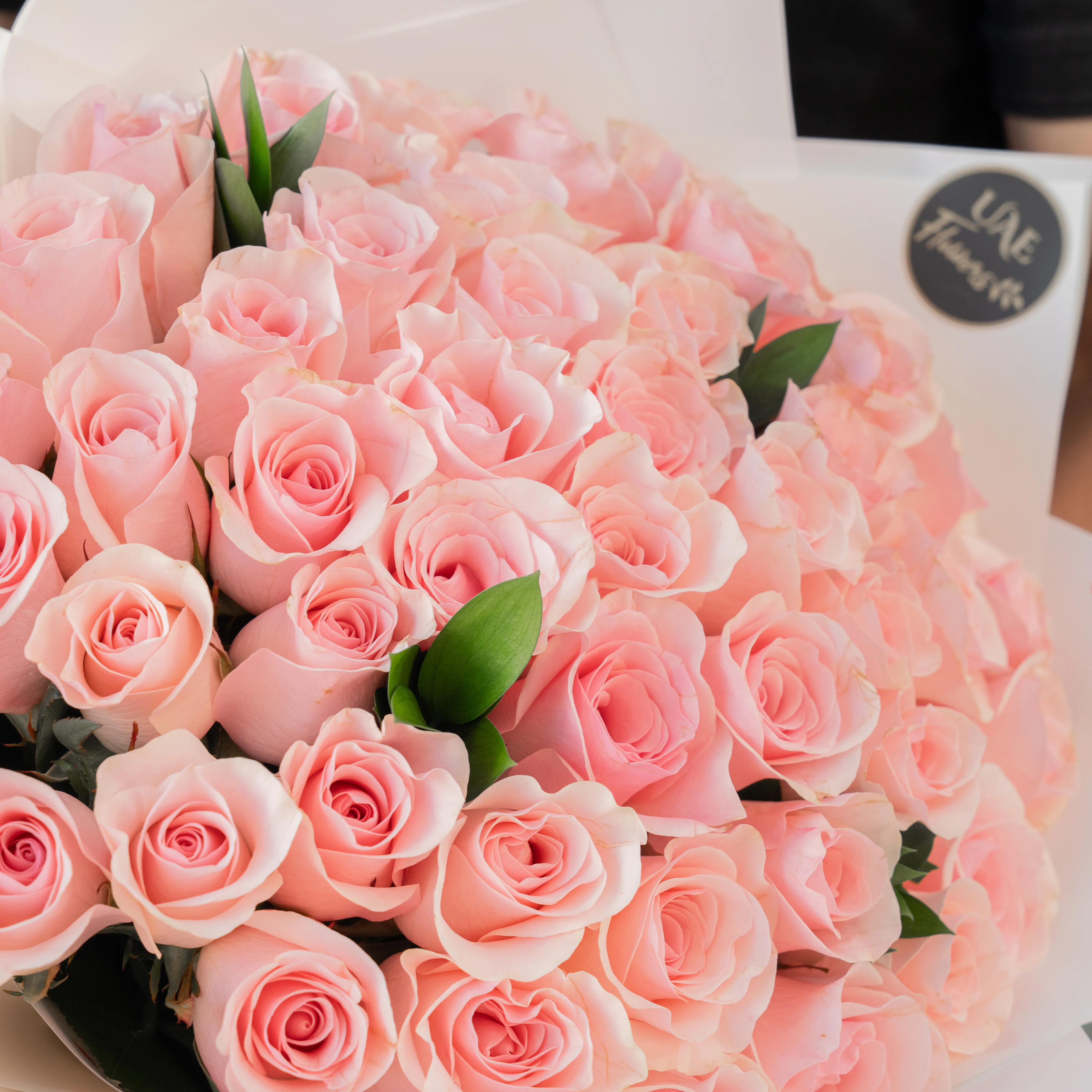 Bouquet of 30 pink roses in paper packing hand-tied with ribbons.