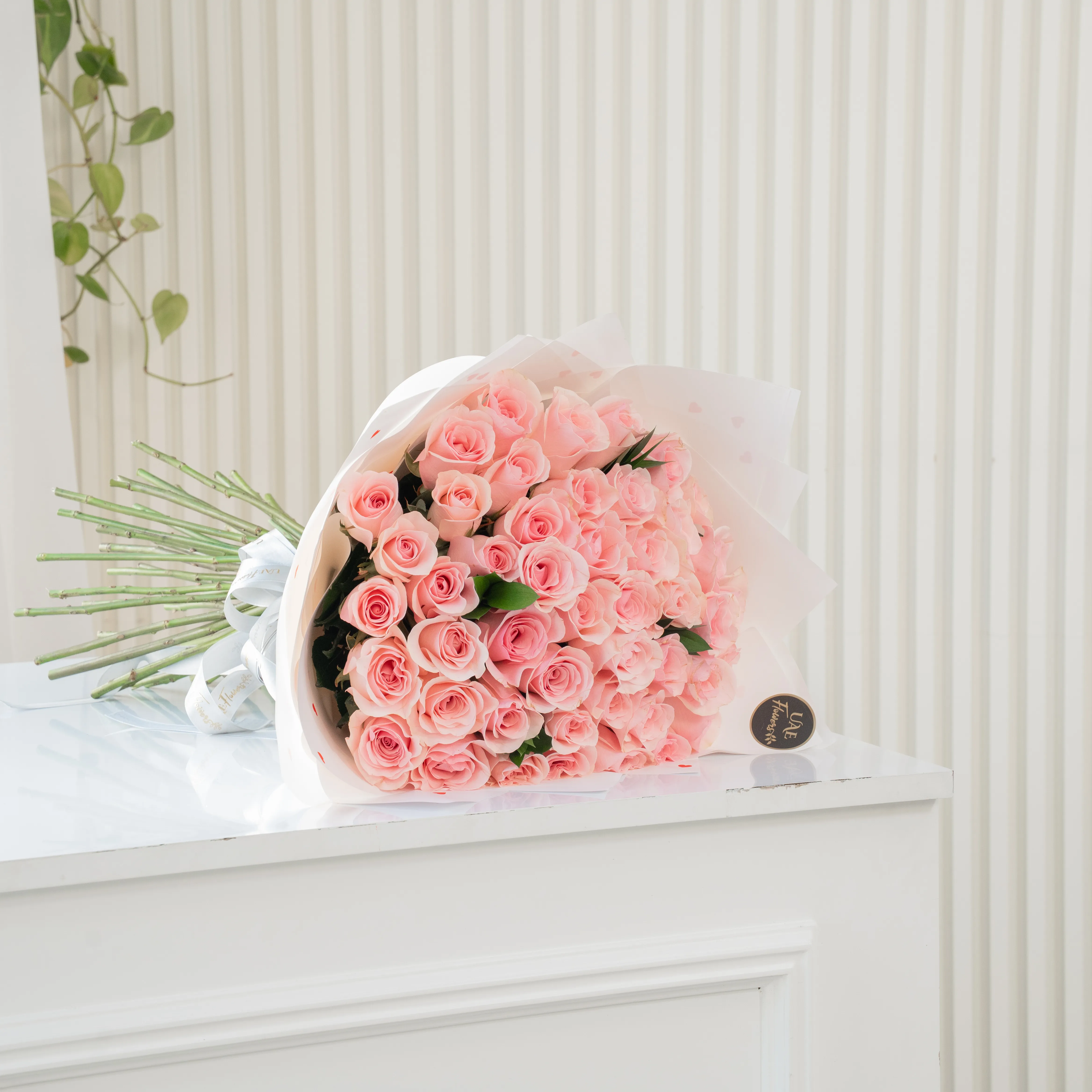 Bouquet of 30 pink roses in paper packing hand-tied with ribbons.
