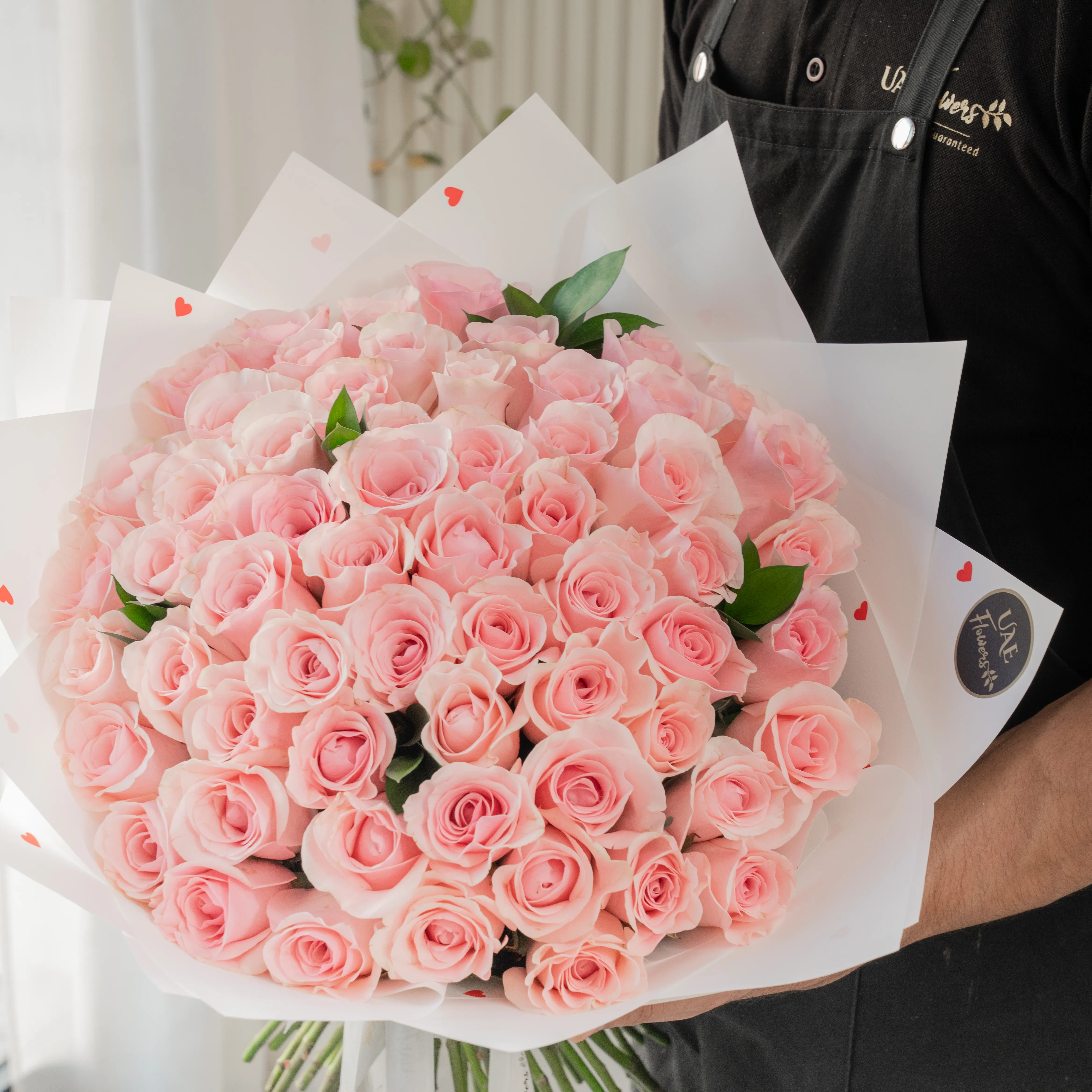 Bouquet of 40 pink roses in paper packing hand-tied with ribbons.