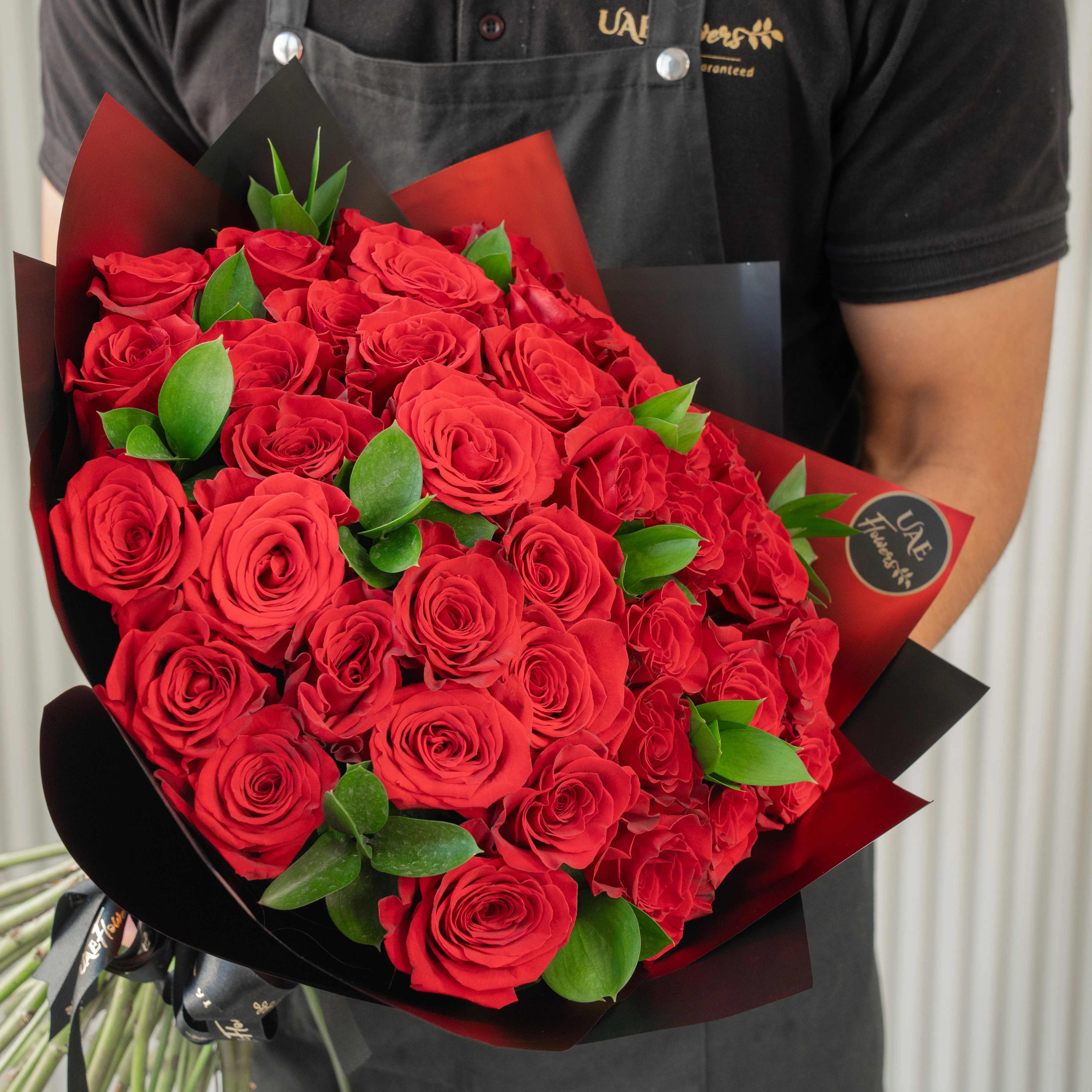 Bouquet of 30 red roses in paper packing hand-tied with ribbons.