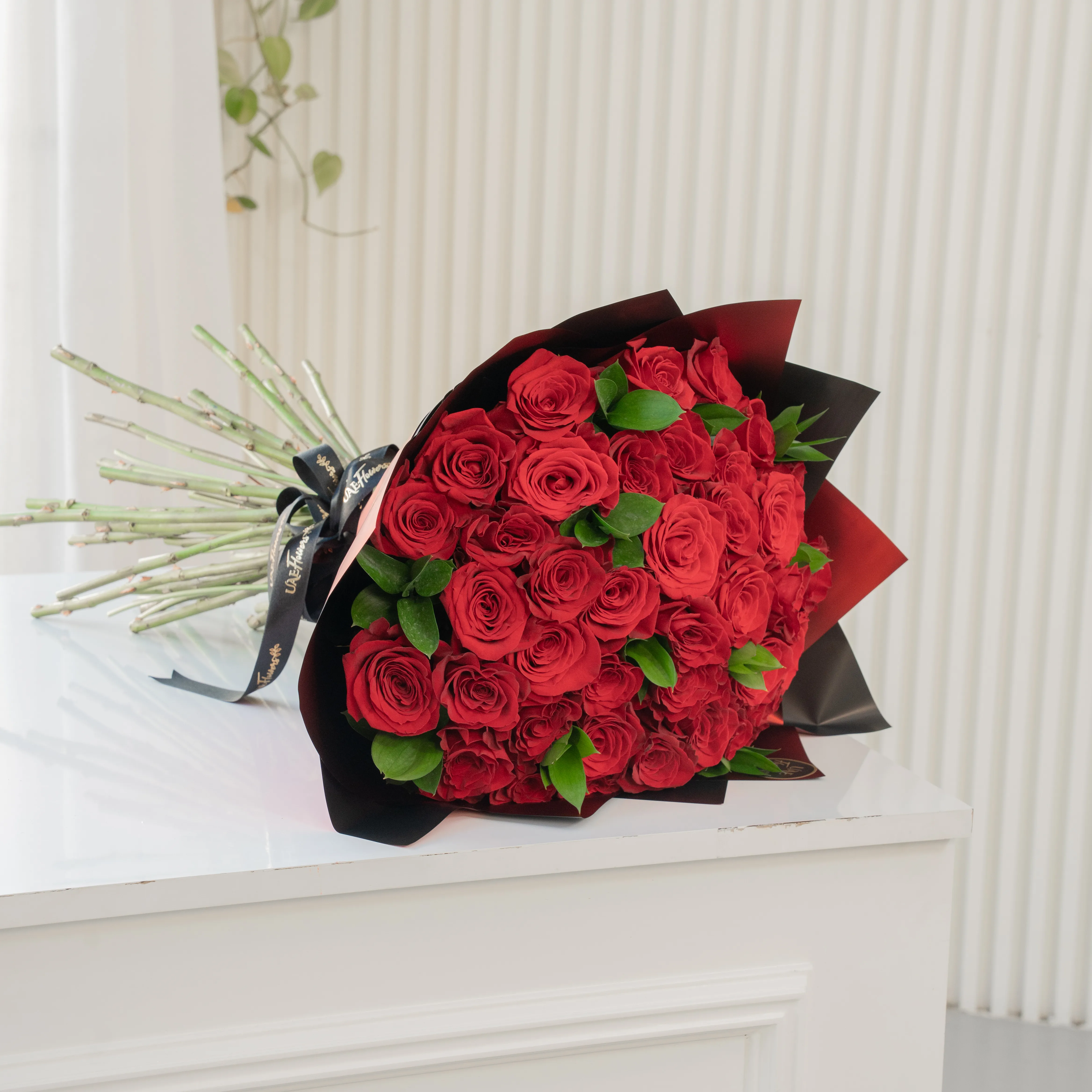 Bouquet of 30 red roses in paper packing hand-tied with ribbons.