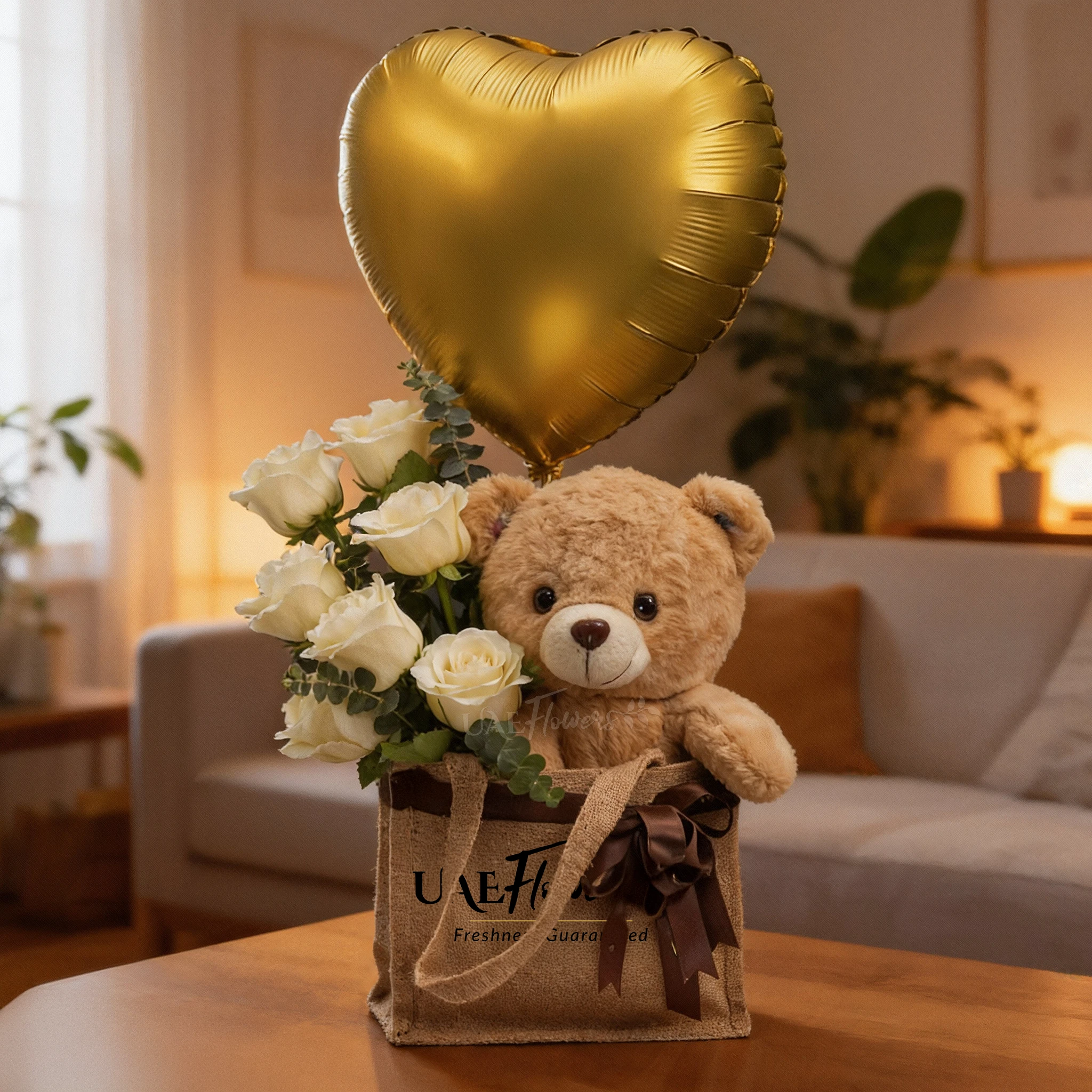 Bouquet of 7 white roses with teddy bear and golden heart balloon in a jute bag tied with ribbon, perfect for birthdays and romantic gifts.