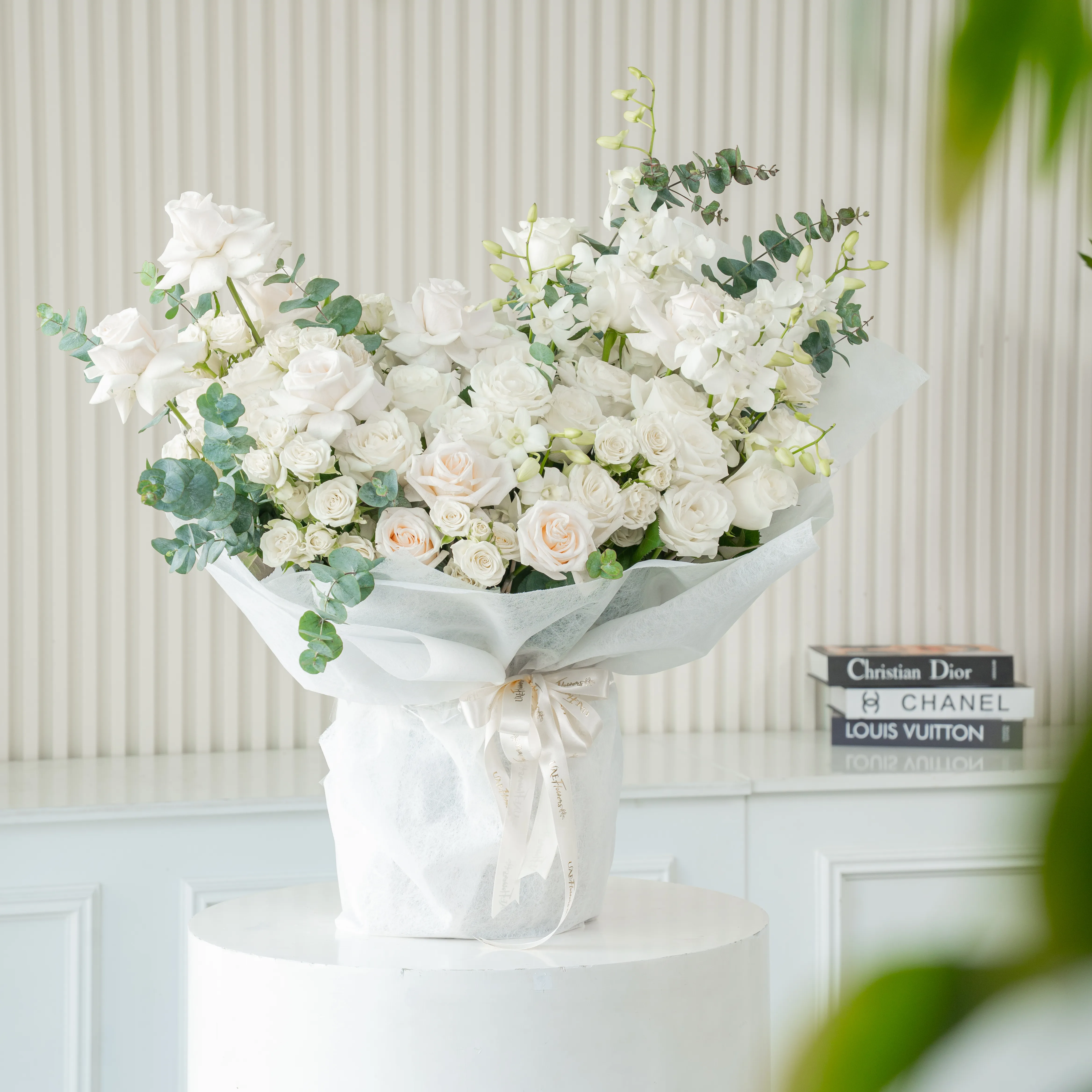 Bouquet of 20 white roses and 10 white spray roses with green fillers in white paper packing tied with white ribbon.