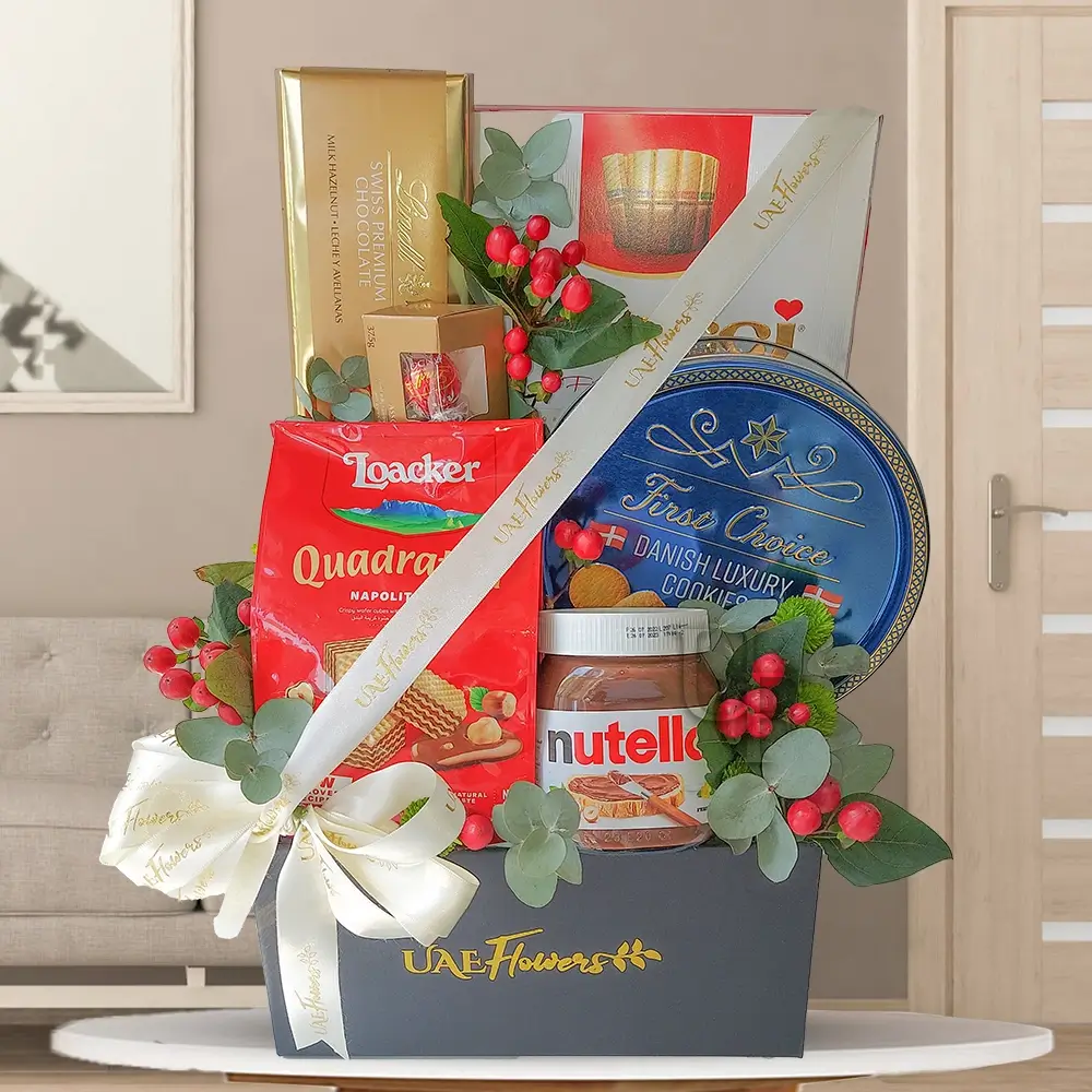 A gift hamper containing chocolates & cookies, along with 2 gold hypericum greens & fillers, all presented in a black box