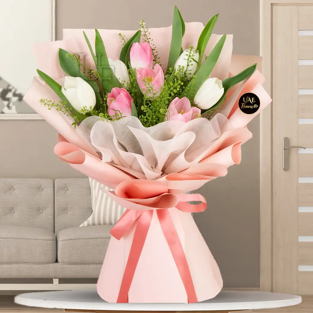 A bouquet of 10 white and pink tulips with fillers, wrapped in pink and white paper tied with pink ribbon