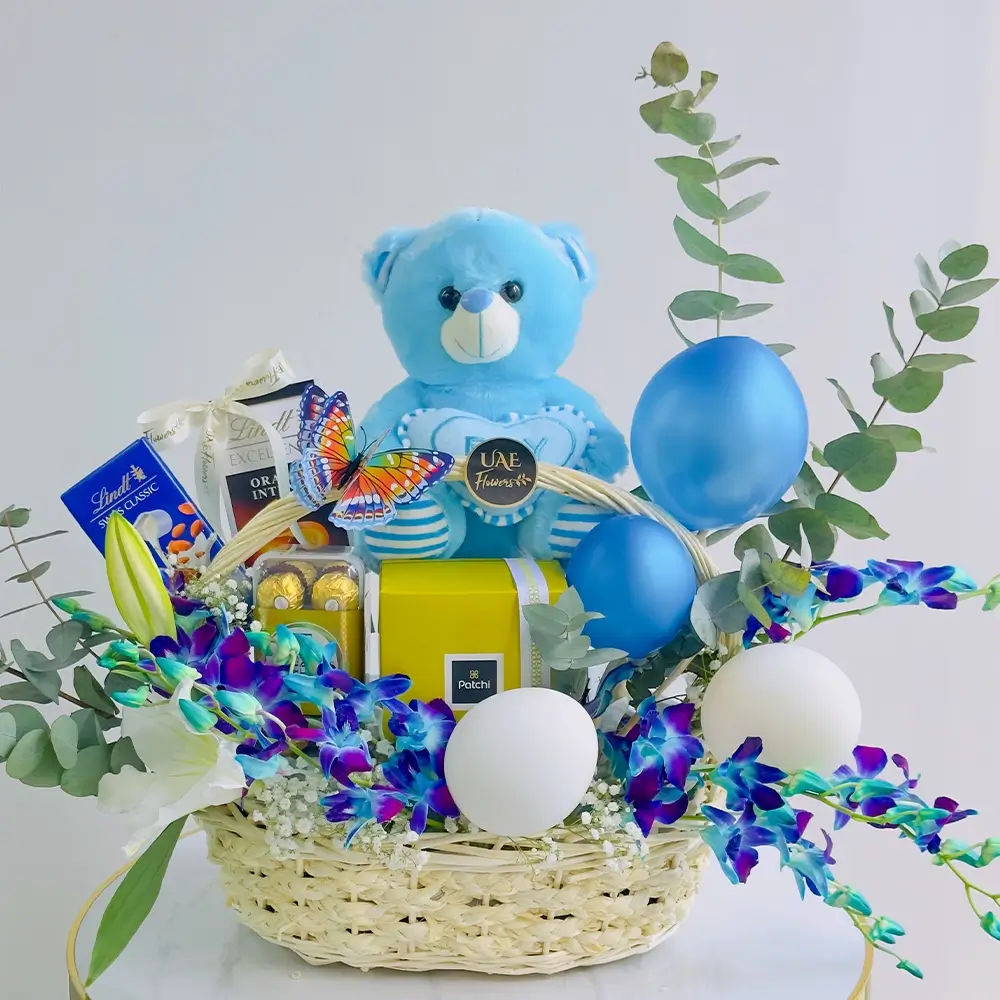 Baby Boy Blue Gift Basket includes a white lily, blue orchids, and a mix of chocolates