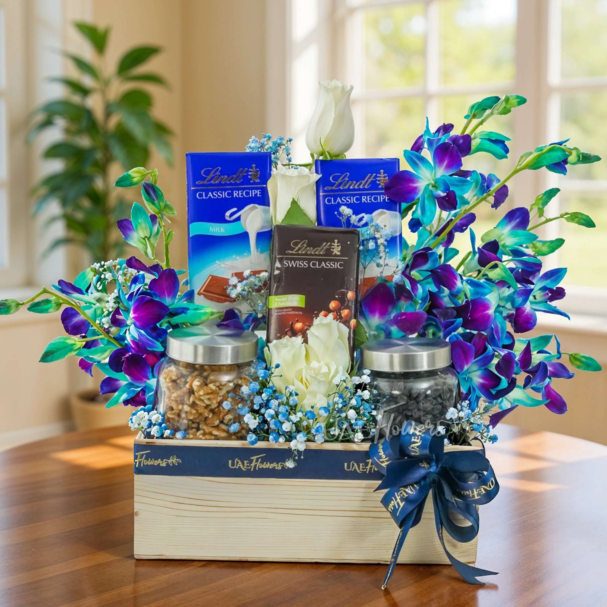An arrangement of 5 white roses and 5 blue orchids, 250 Gms of Walnuts and 250 Gms of black raisins with 2 pcs of Lindt Swiss Classic Milk Chocolate, Lindt Swiss Classic Dark Chocolate with baby's breath fillers in a wooden box.