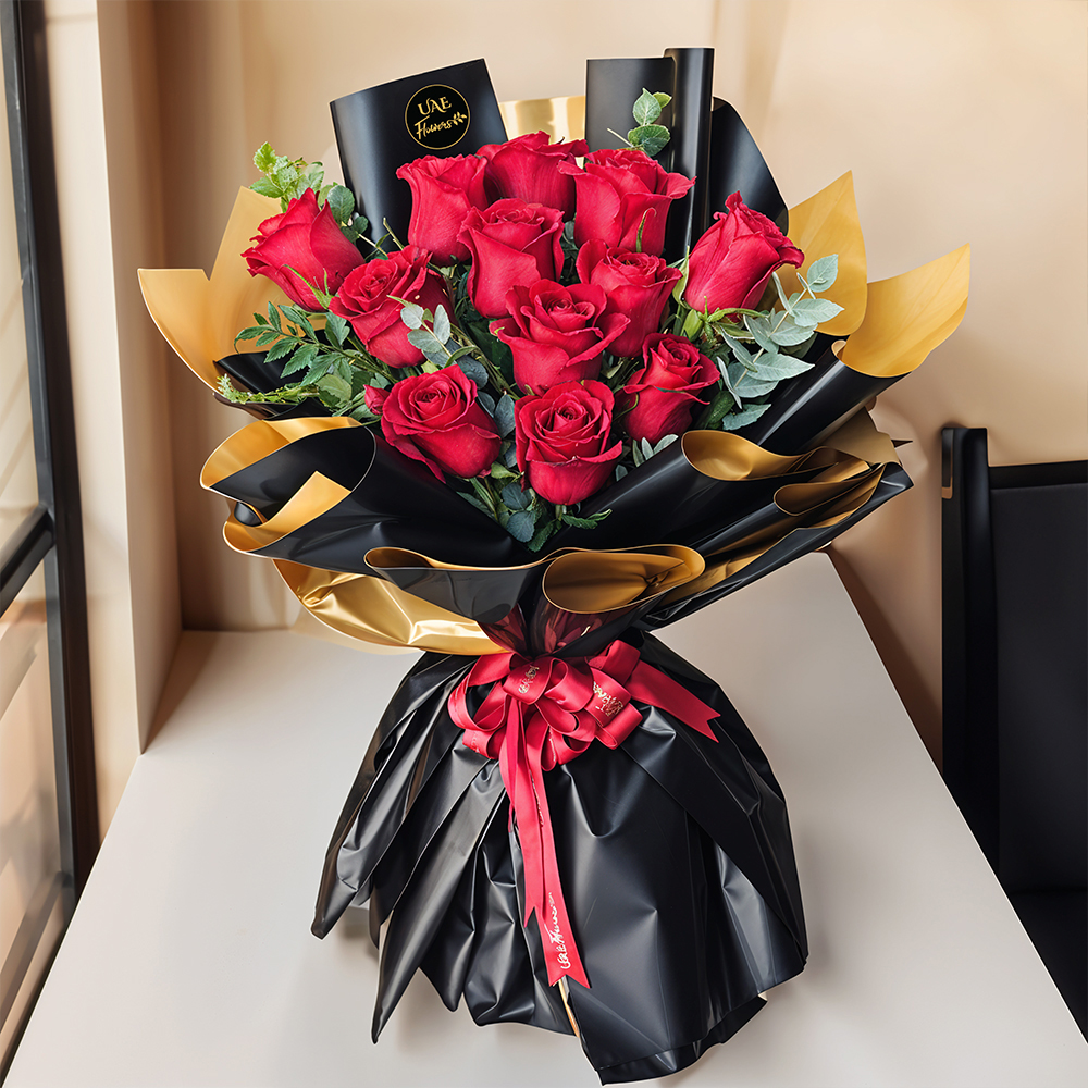 Bouquet of 12 stems of red roses with green fillers in black & gold wrapping paper along with a 12-inch Teddy Bear.