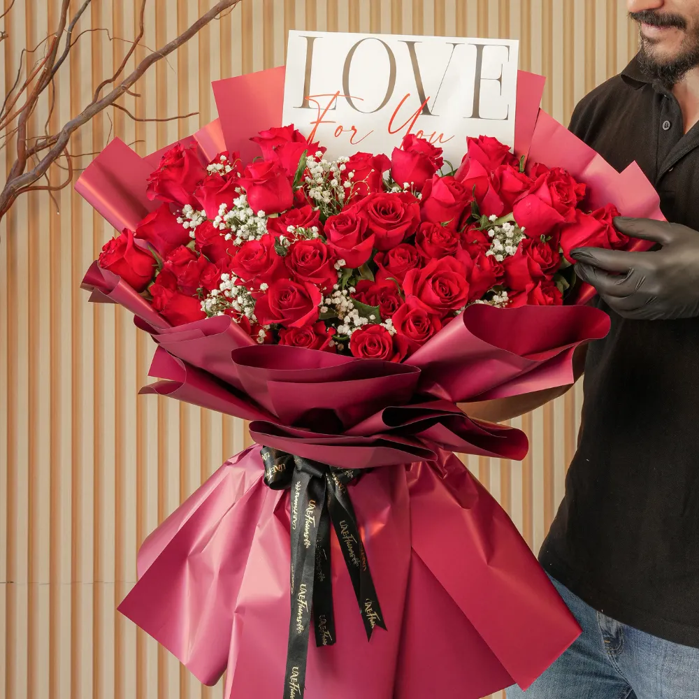 Bouquet of 50 red roses with baby’s breath fillers in red paper wrapping tied with black ribbons