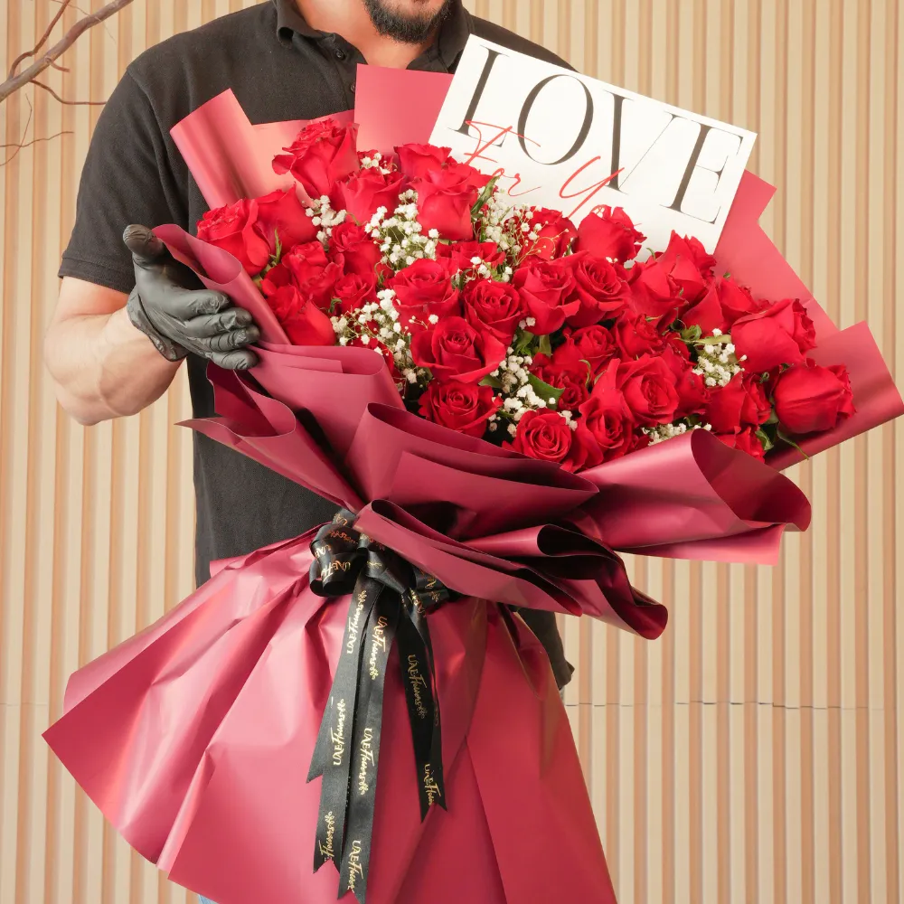 Bouquet of 50 red roses with baby’s breath fillers in red paper wrapping tied with black ribbons
