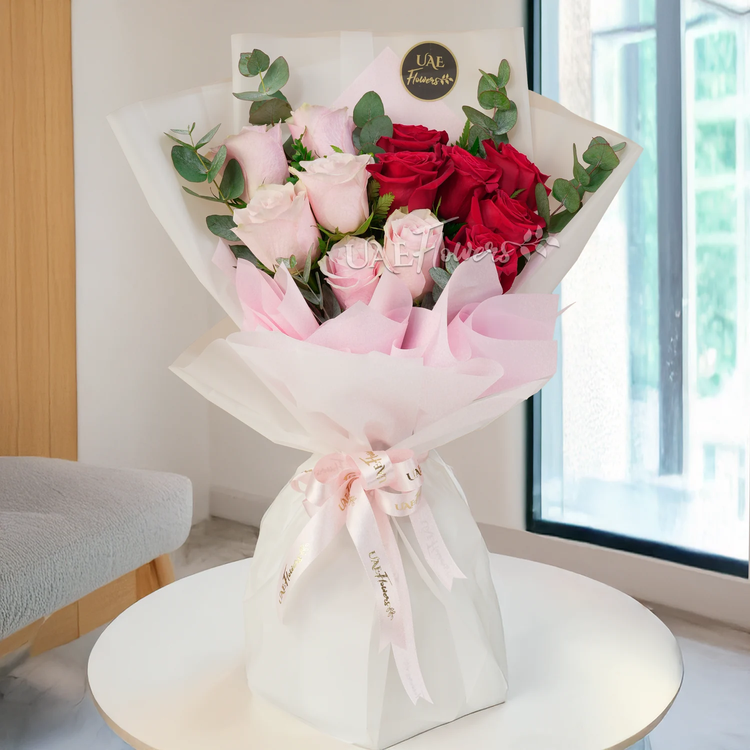 A bouquet of 6 pink roses and 6 red roses with eucalyptus leaf and green fillers in brown wrapping paper tied with brown ribbon and a 12 inch pink teddy