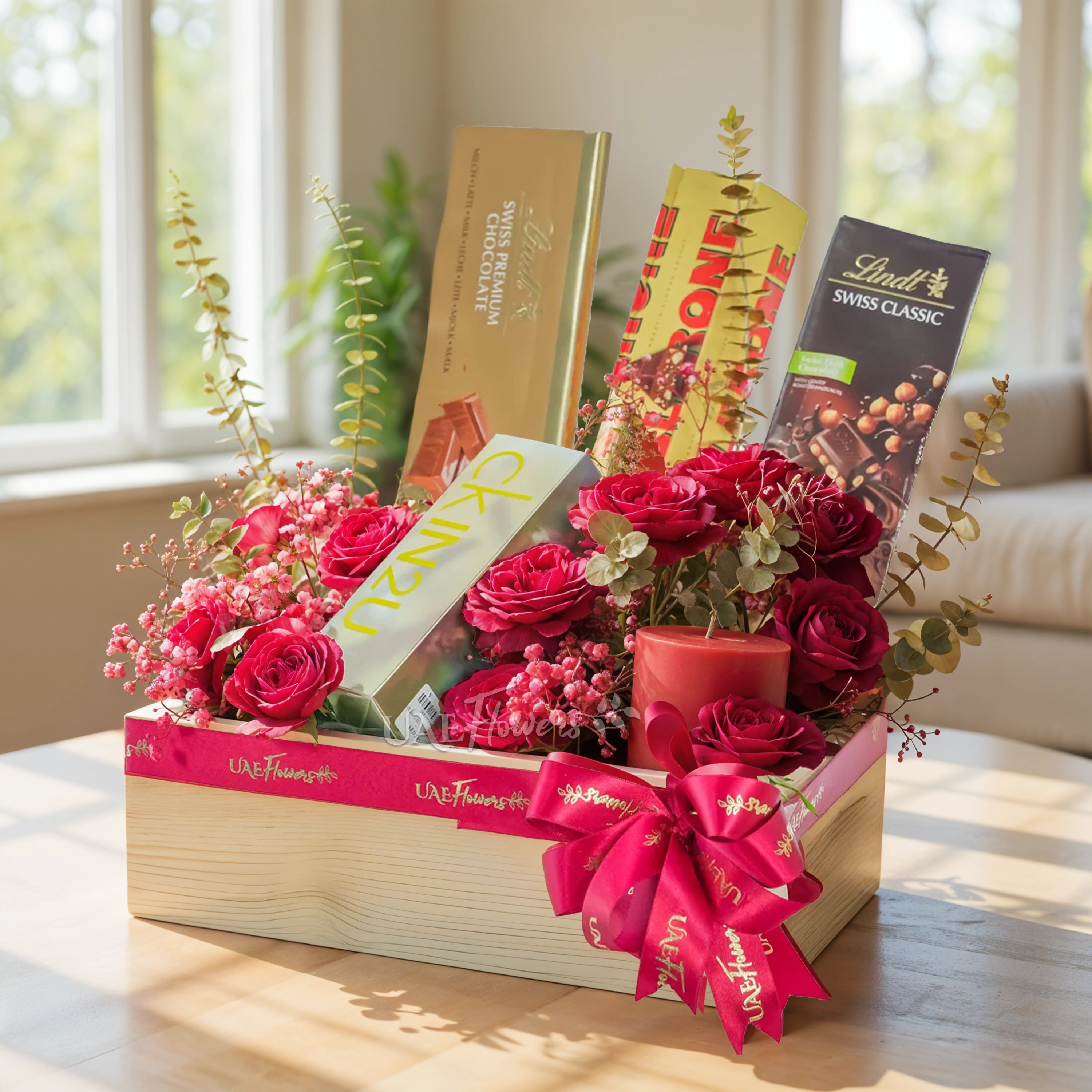 A wooden box arrangement of 12 red roses, 6 Pcs Toblerone Chocolates, Lindt Swiss Dark Chocolate Classic 100g, Lindt Swiss Premium Chocolate Bar 300g and CK In2u L EDT 100ML perfume with gold sprayed eucalyptus leaf and baby's breath.