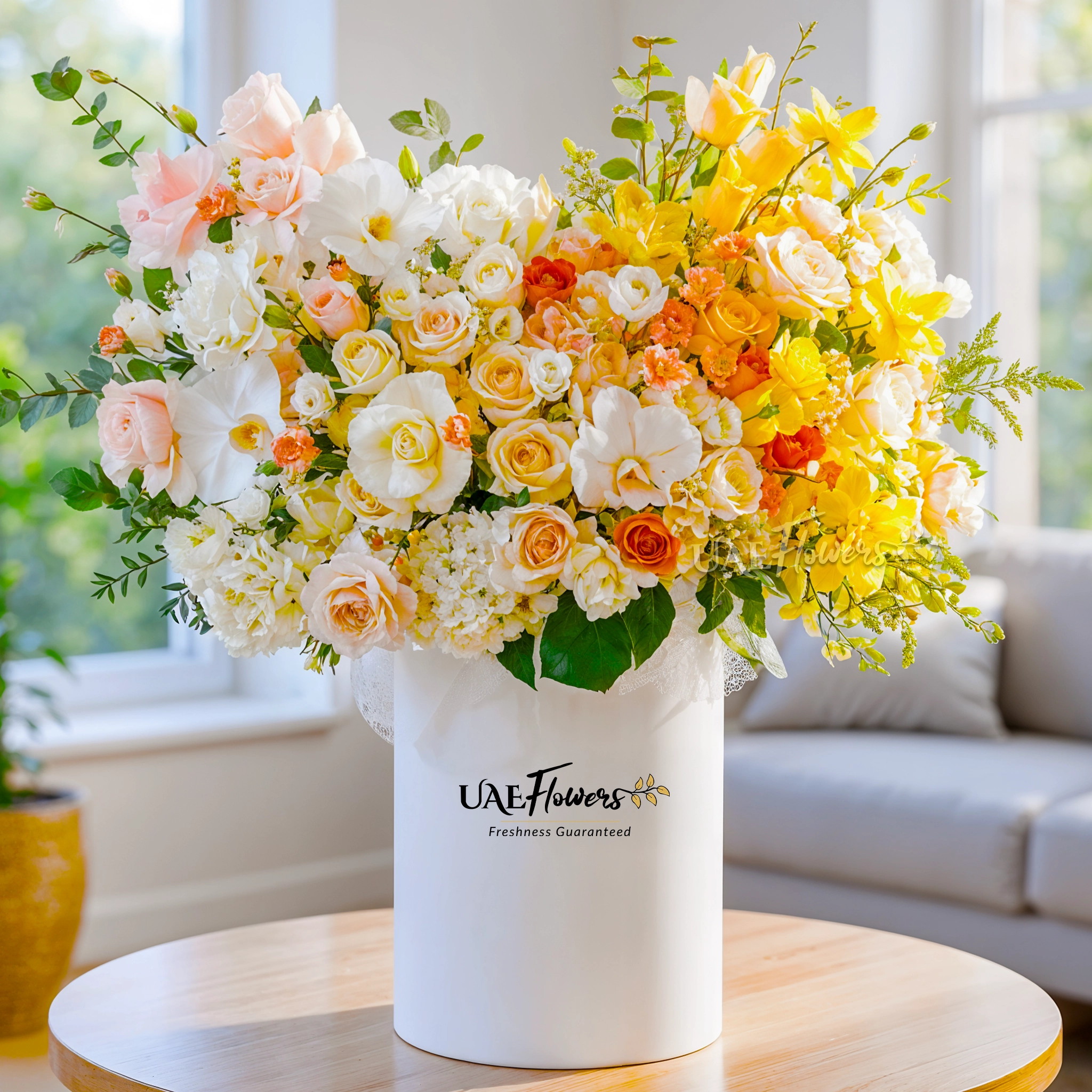 An arrangement of white lisianthus, peach spray carnations, white hydrangeas, yellow roses, orange roses, peach roses, cream roses, sprayed Yellow roses, sprayed yellow orchids and white cymbidium orchid with green fillers in a tall round box.