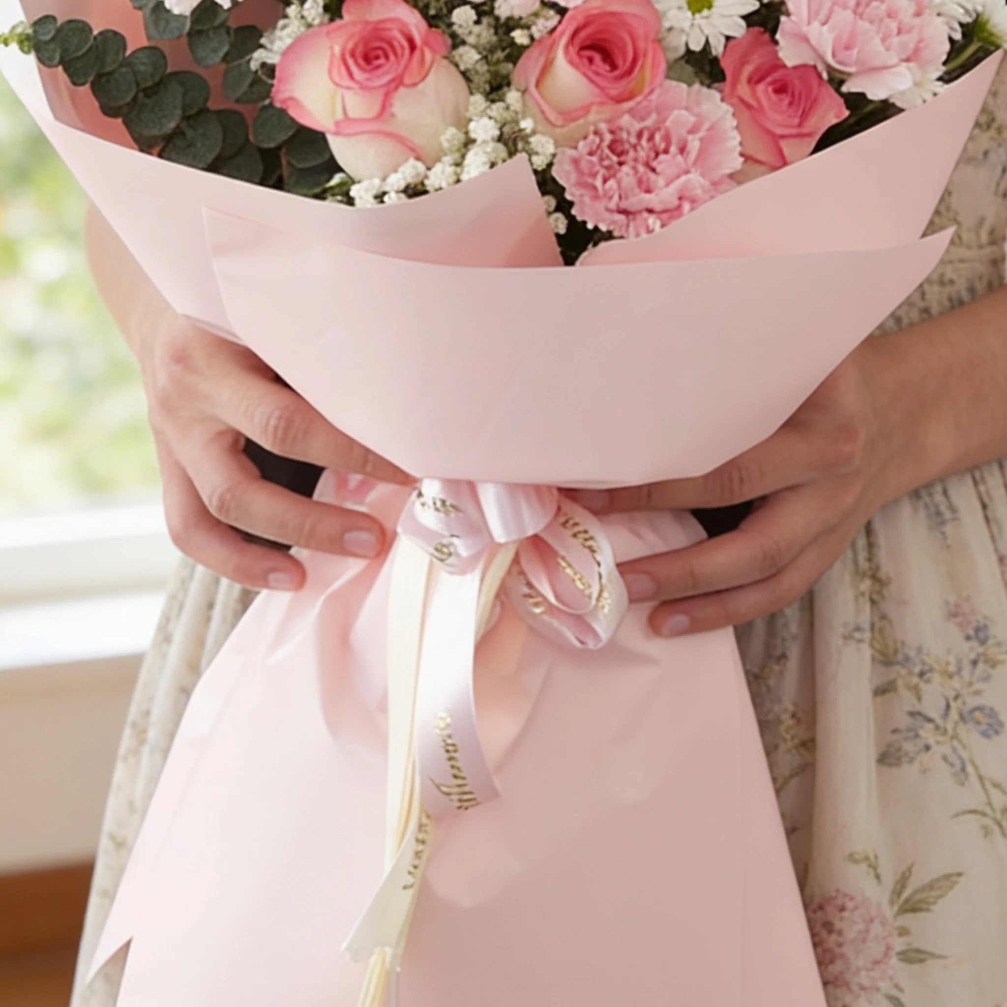 Bouquet of 7 pink roses, 6 pink carnations, 2 white chrysanthemums with green fillers in pink wrapping.
