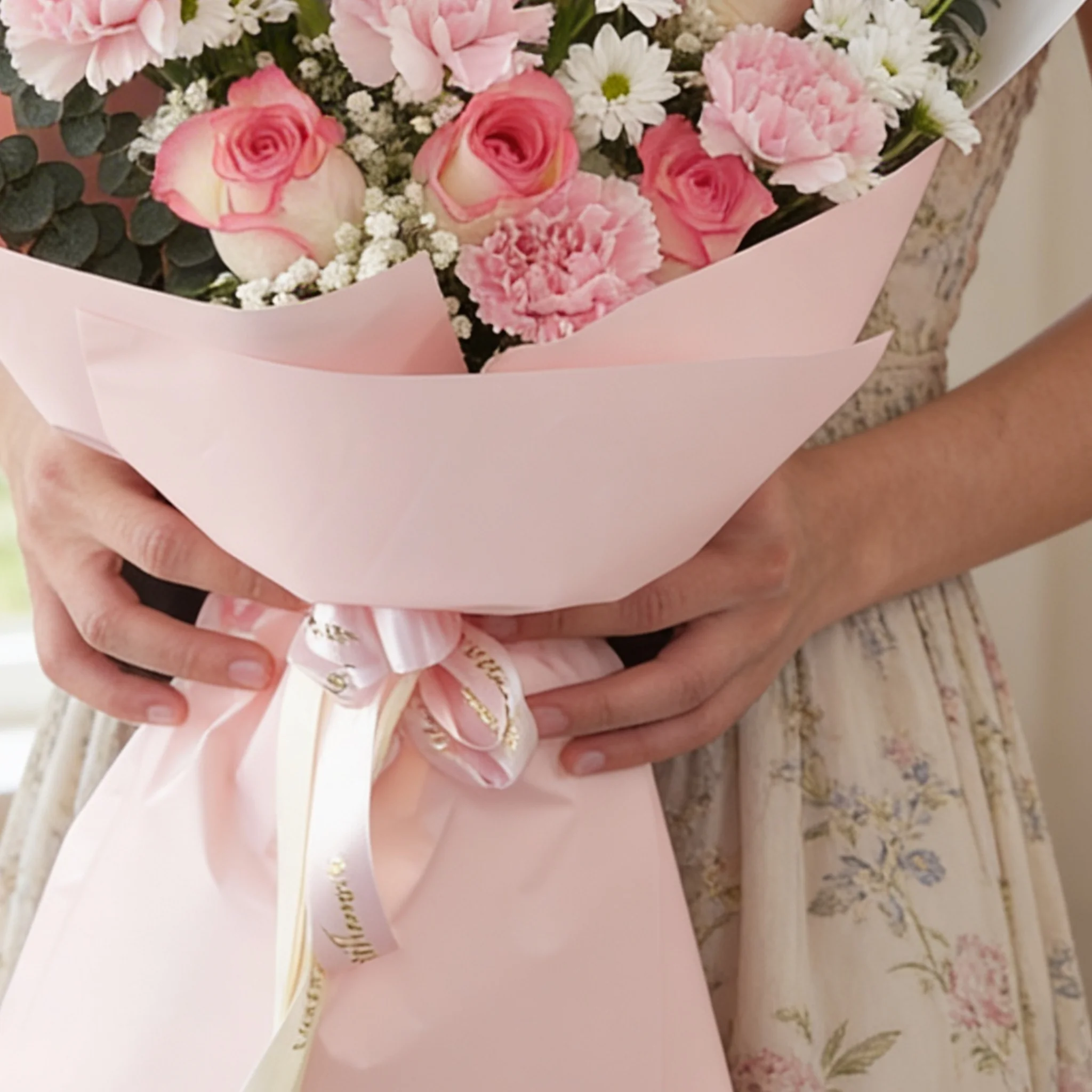 Bouquet of 7 pink roses, 6 pink carnations, 2 white chrysanthemums with green fillers in pink wrapping.