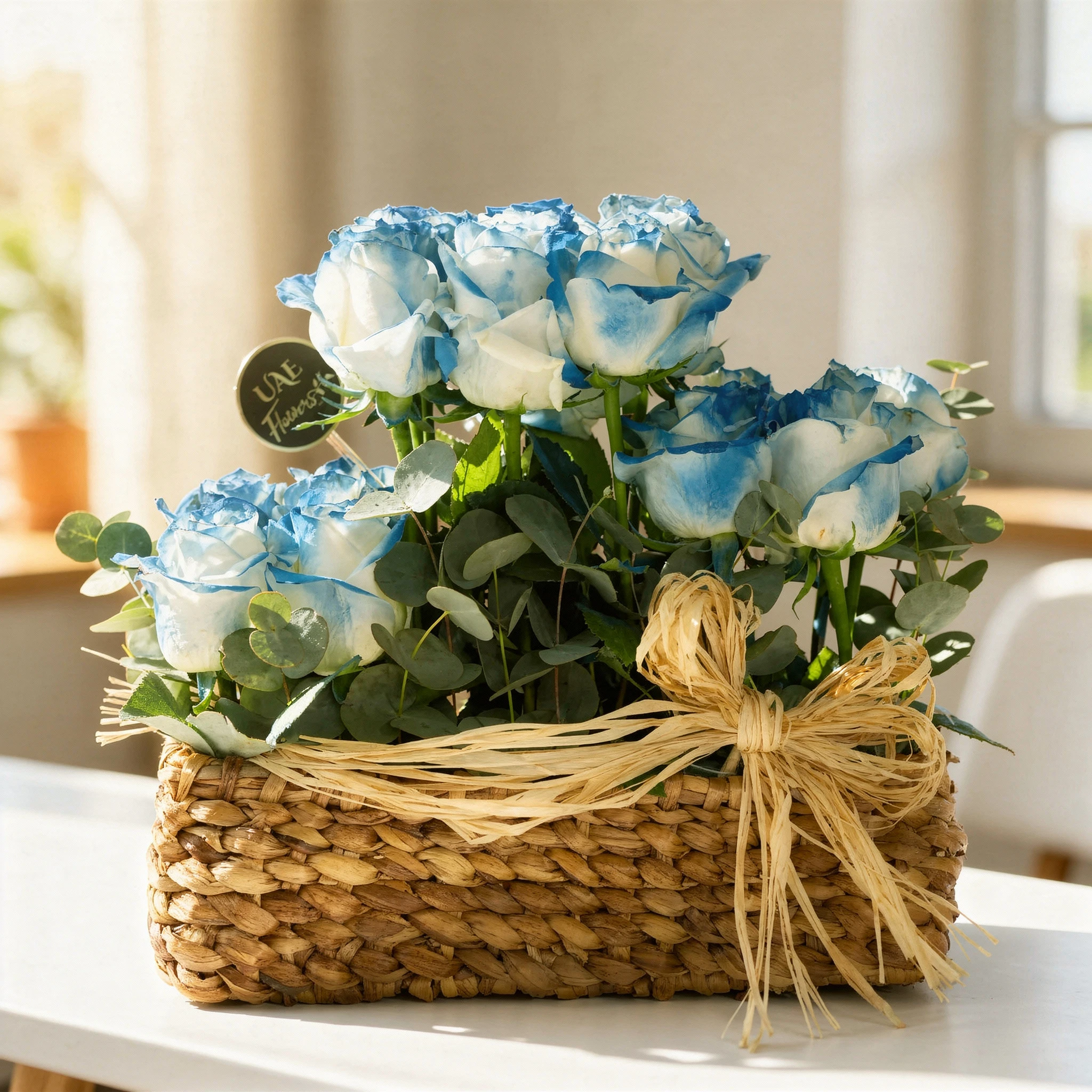 Beautiful blue roses arranged in a rustic woven basket with greenery, tied with a natural raffia bow, perfect for gifting or home decor.