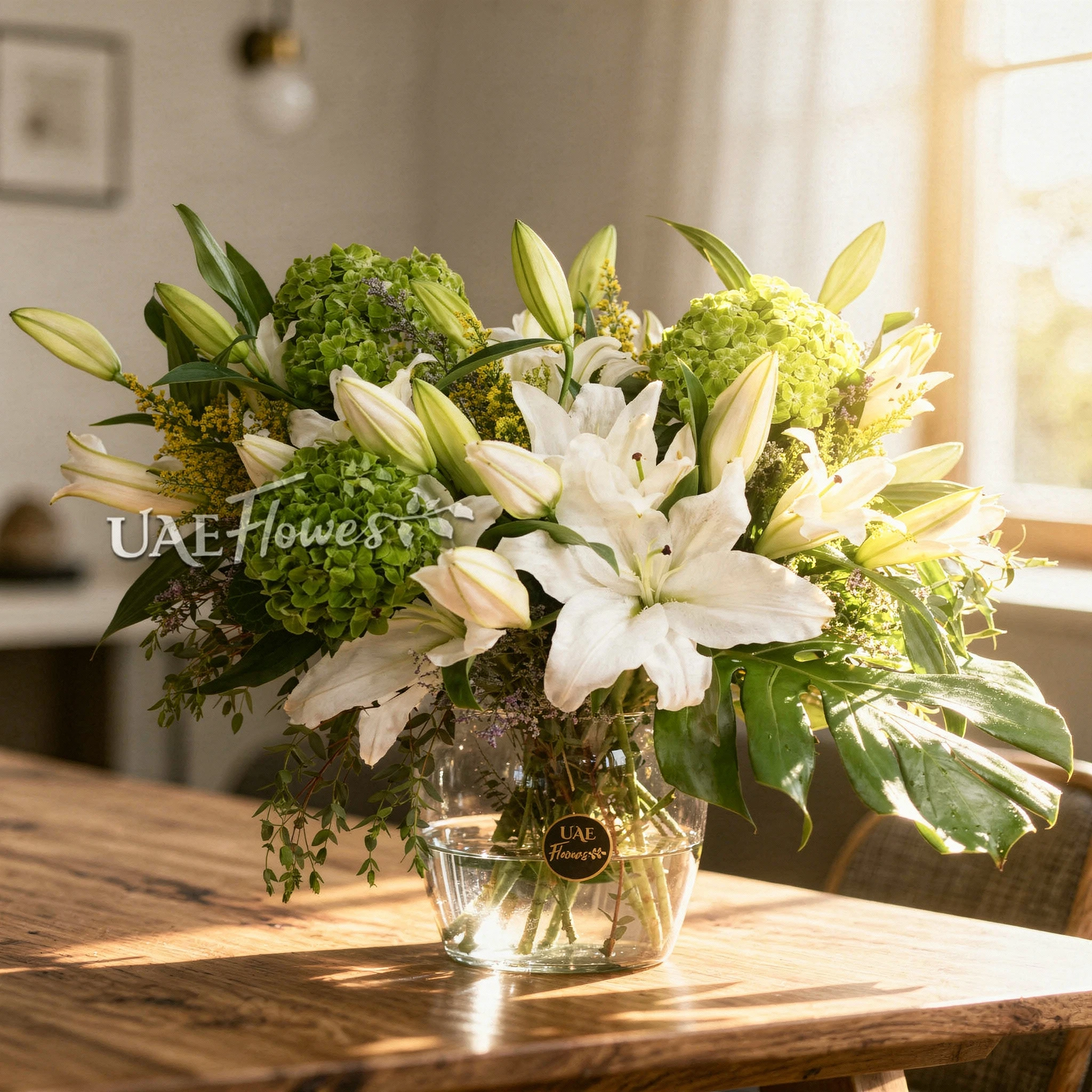 Jade Allure with a sleek glass vase with 8 white lilies, 3 green hydrangeas, 1 monstera leaf, and green fillers.