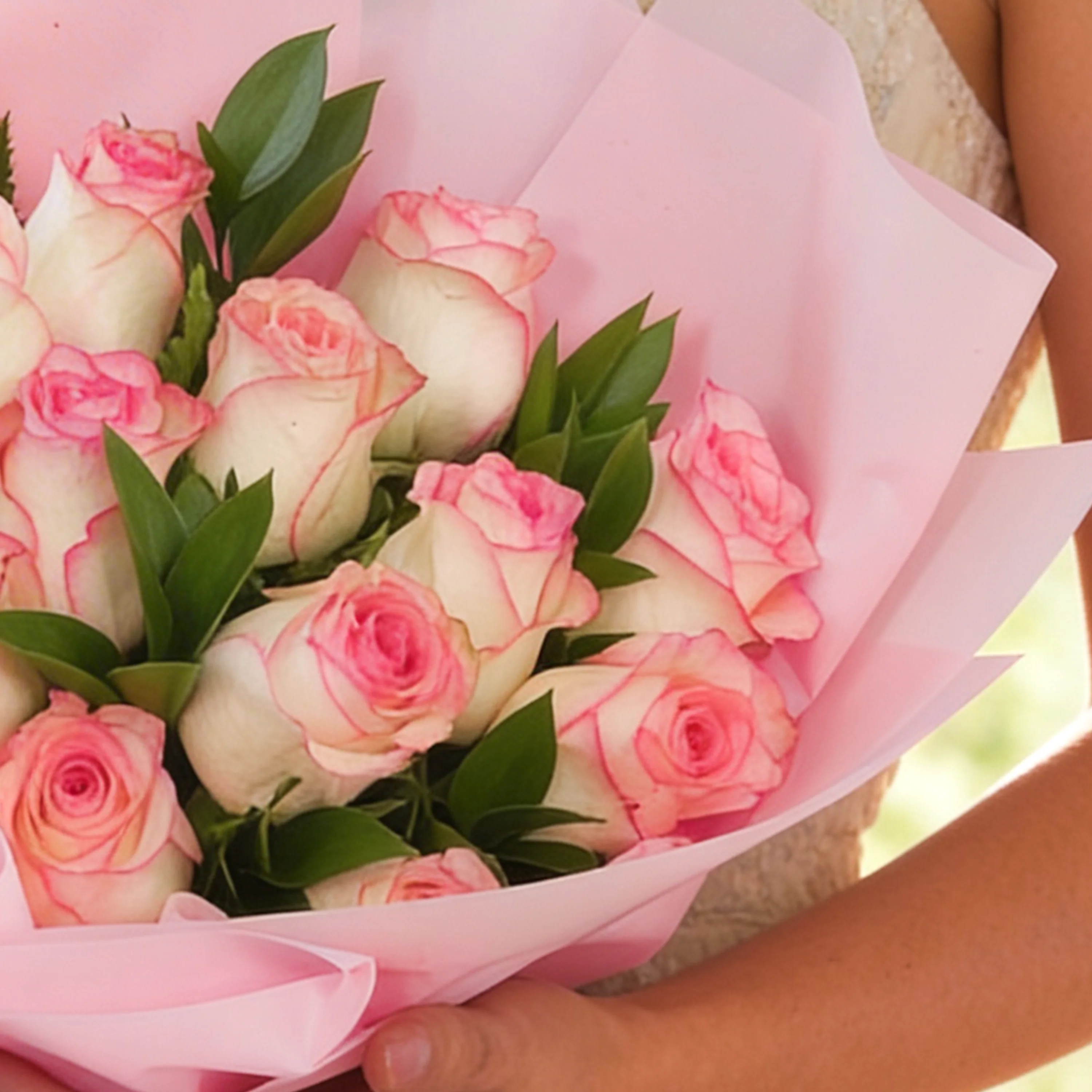 Bouquet of 12 pink roses with green fillers in pink wrapping paper.