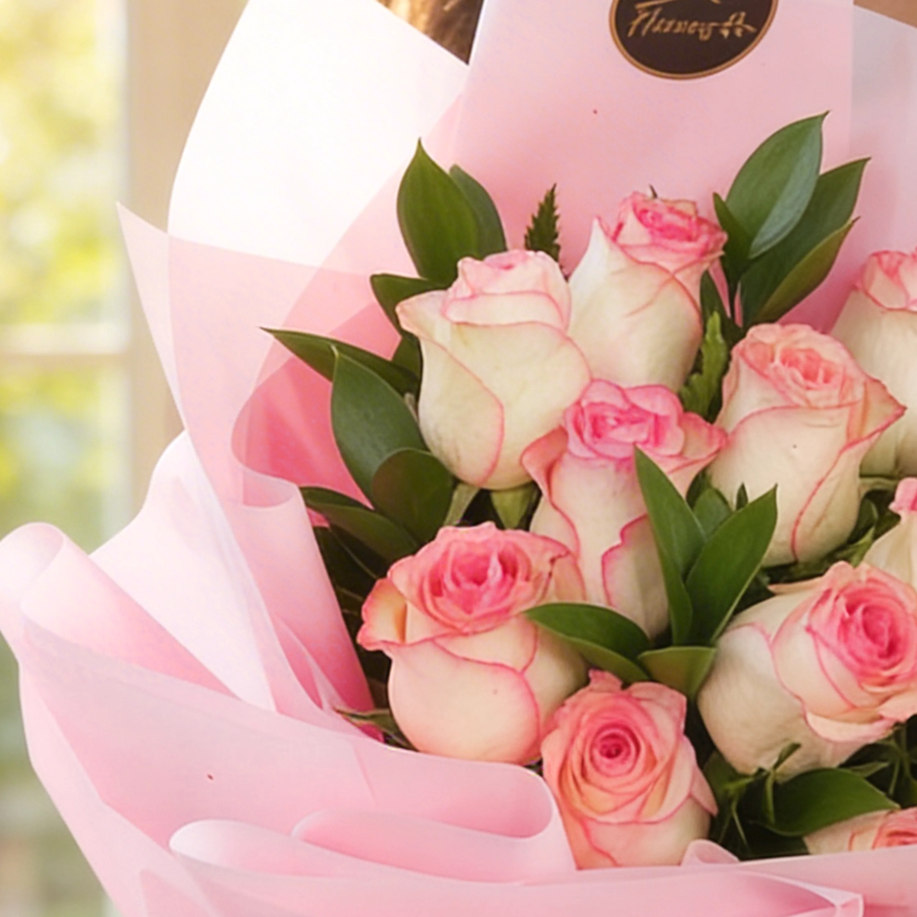 Bouquet of 12 pink roses with green fillers in pink wrapping paper.