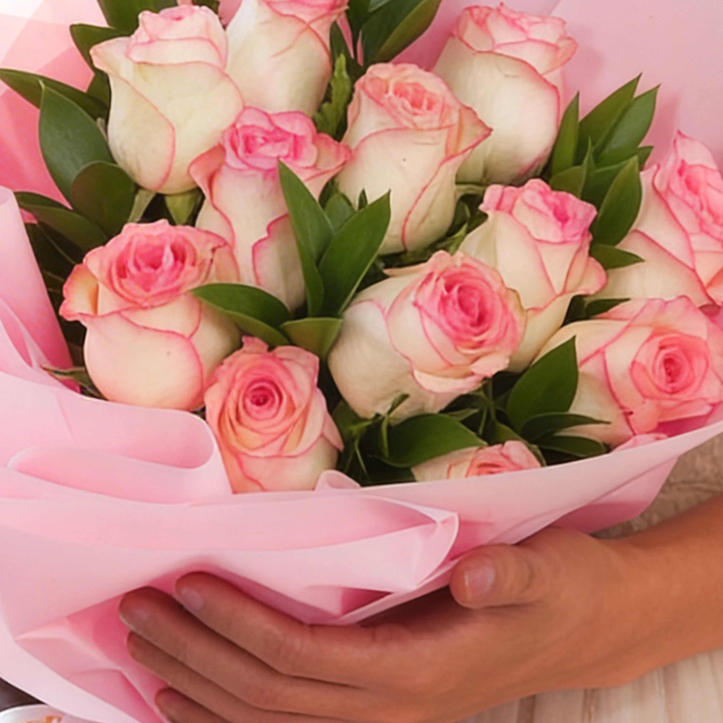 Bouquet of 12 pink roses with green fillers in pink wrapping paper.