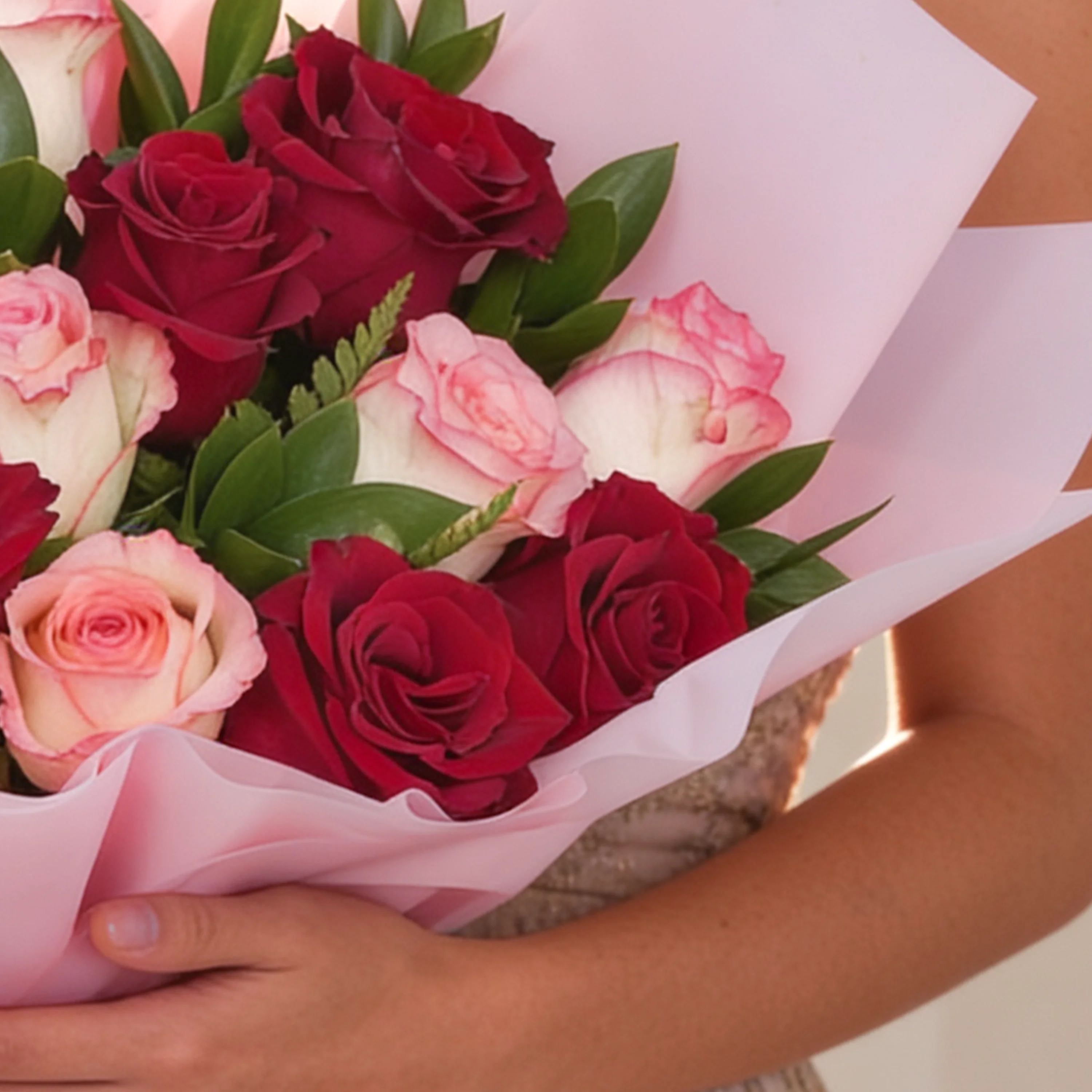 Bouquet of 12 red and pink roses with green fillers in pink wrapping paper.
