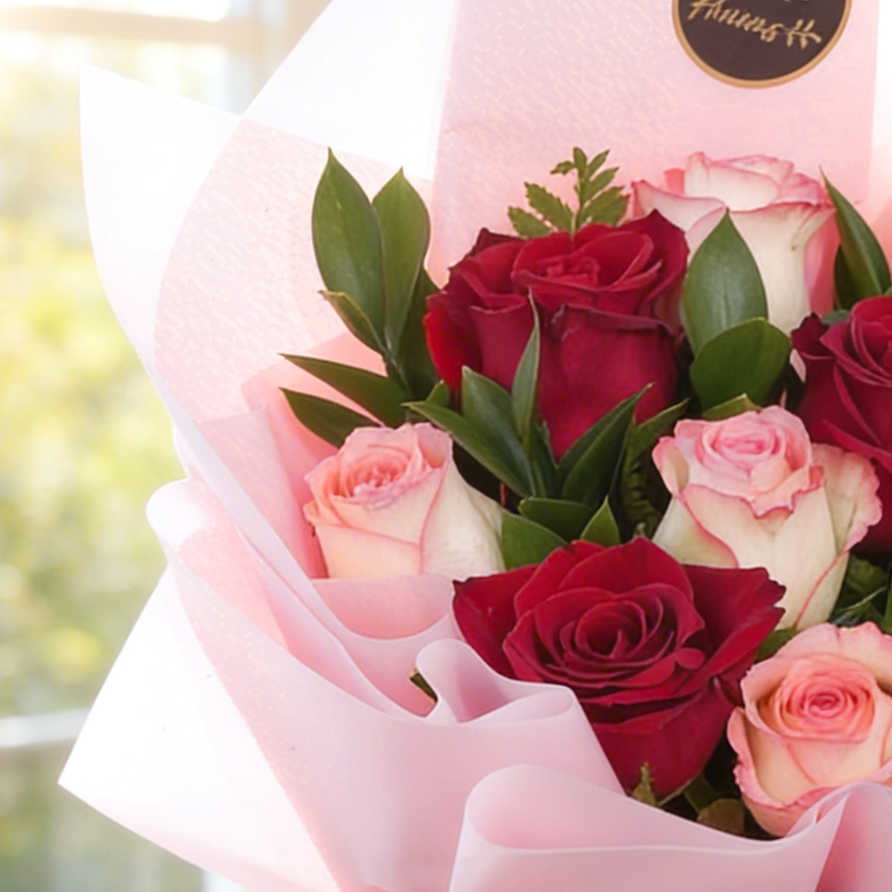 Bouquet of 12 red and pink roses with green fillers in pink wrapping paper.