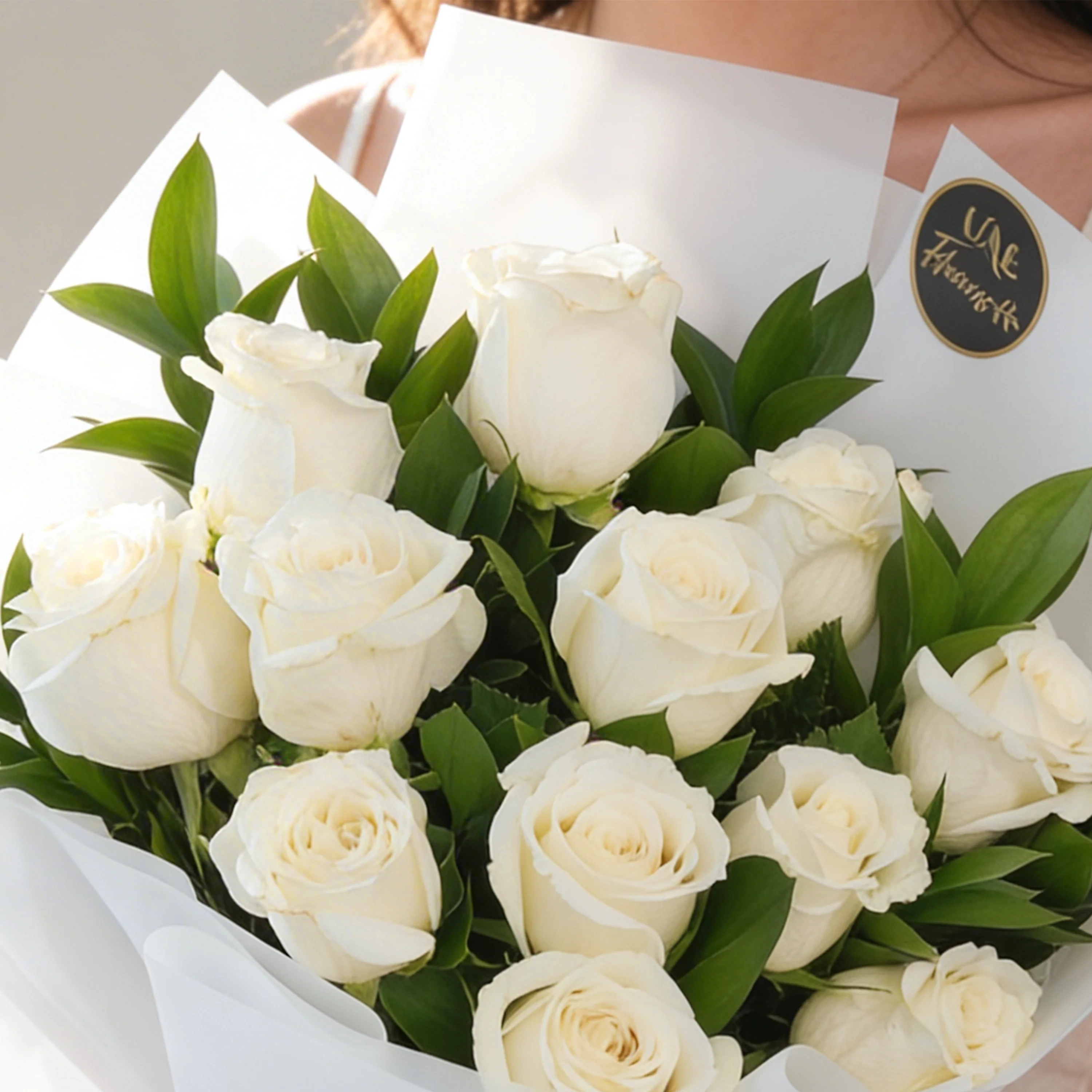 Bouquet of 12 white roses with green fillers in white wrapping paper.