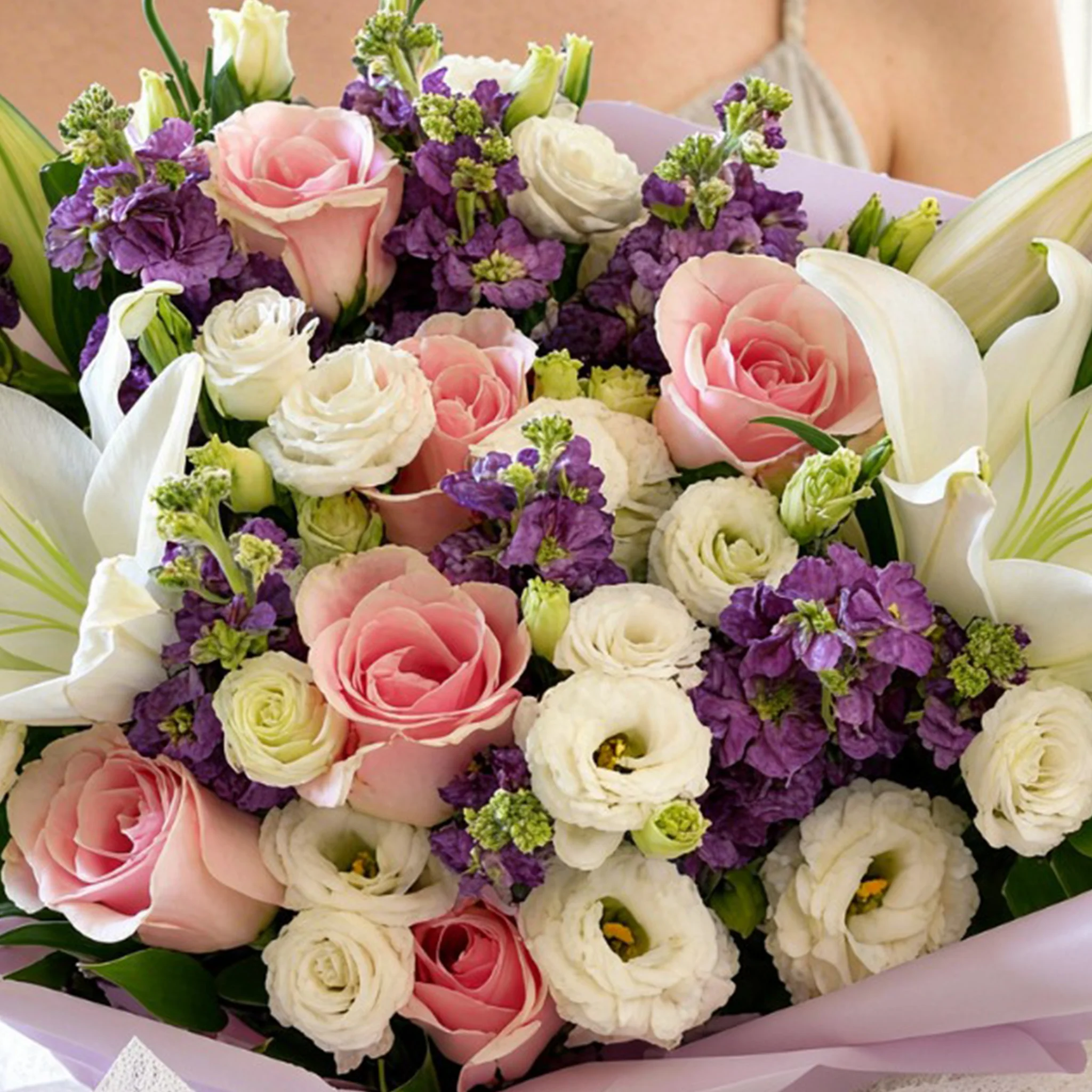 Bouquet of 2 white lilies, 10 purple matthiola, 5 white lisianthus and 8 pink roses with green fillers in nice wrapping.