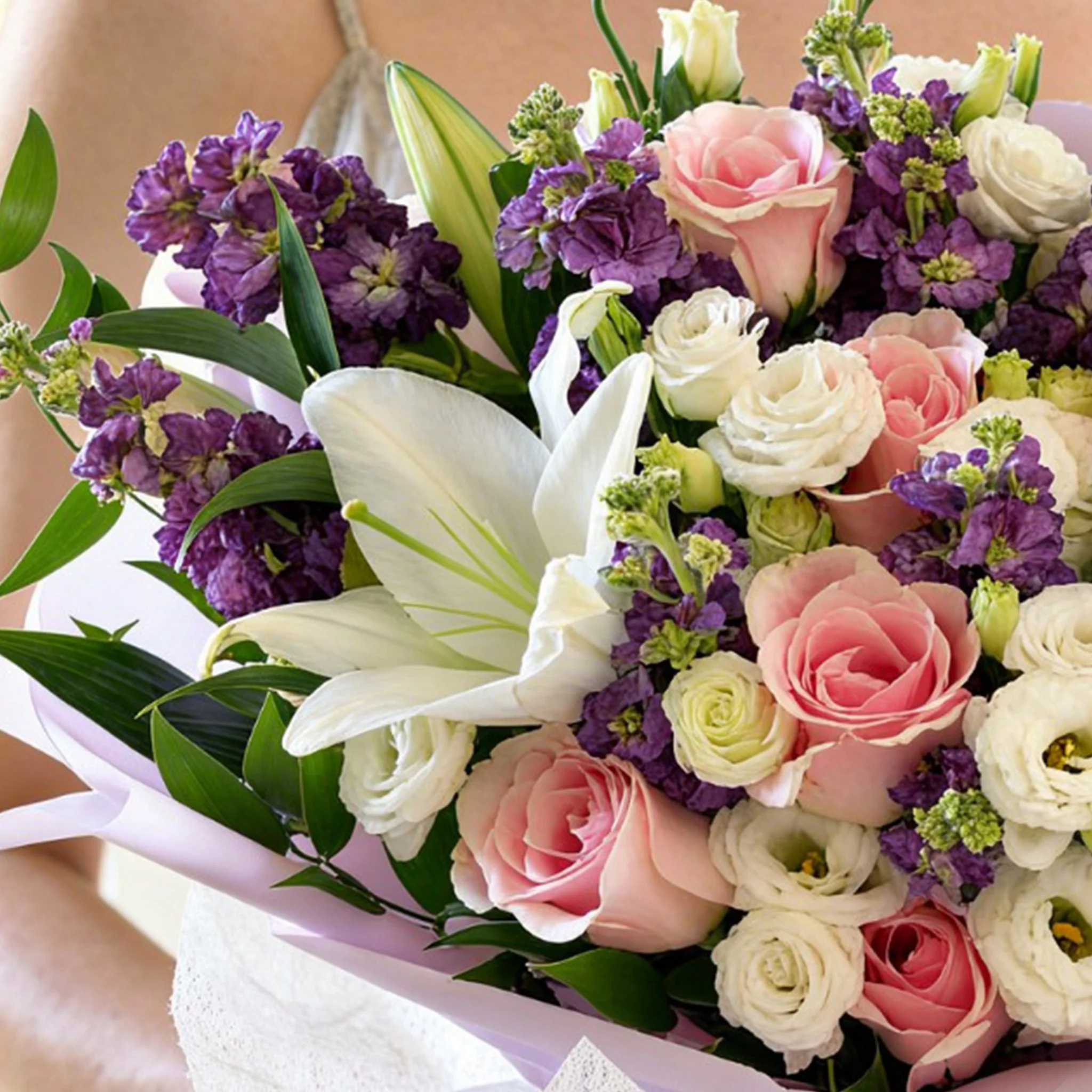 Bouquet of 2 white lilies, 10 purple matthiola, 5 white lisianthus and 8 pink roses with green fillers in nice wrapping.