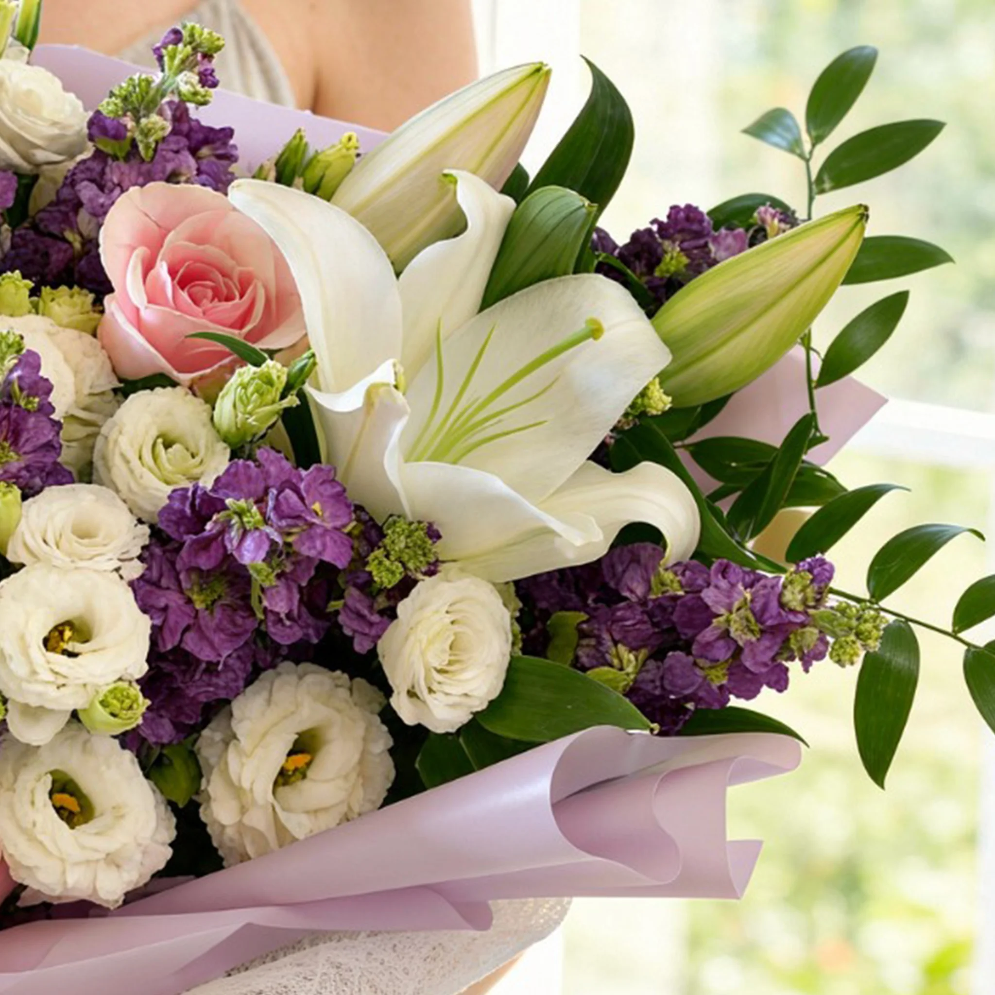 Bouquet of 2 white lilies, 10 purple matthiola, 5 white lisianthus and 8 pink roses with green fillers in nice wrapping.